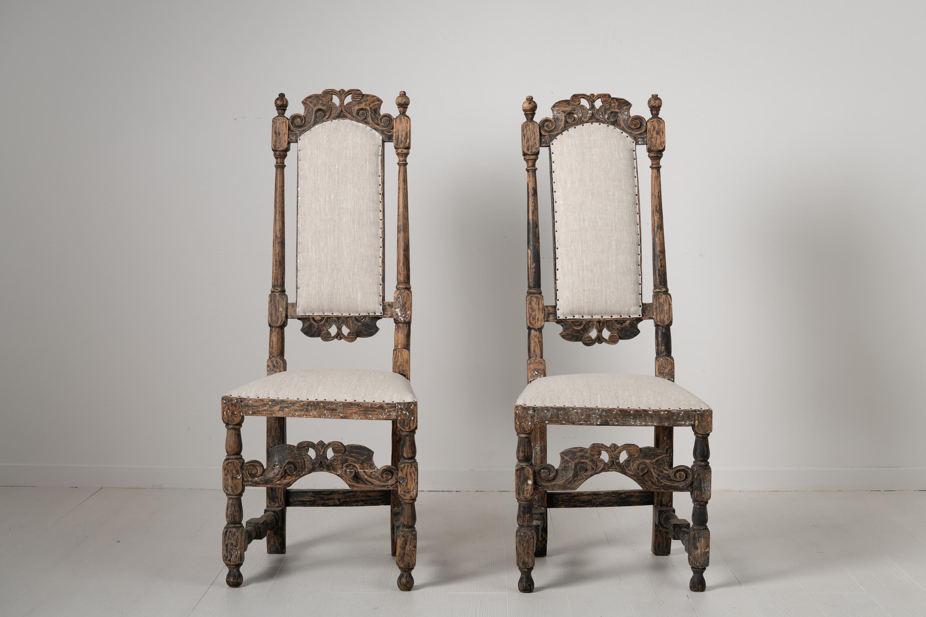 Swedish mid 18th century pair of baroque chairs. The chairs are hardwood and dry scraped to old historic paint. They have an ornate wooden decor carved by hand, the backrest and front are especially detailed. Completely renovated seats with new