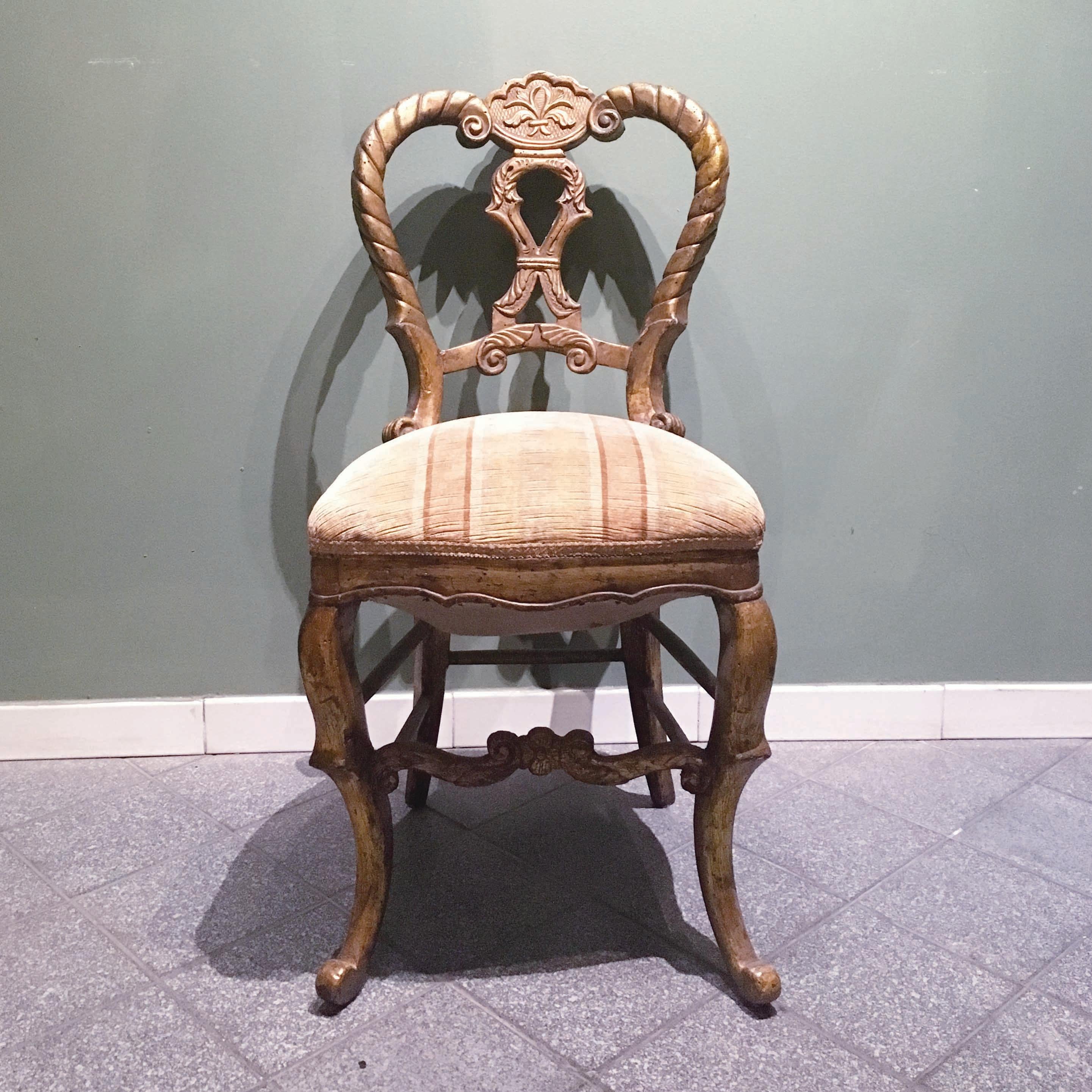 An elegant set of four Italian chairs in solid carved and giltwood. The chairs present a beautiful Silhouette with elegant lines, a carved decoration on the curved back and curved legs. A new upholstering would be needed. Manufactory of the Marches,