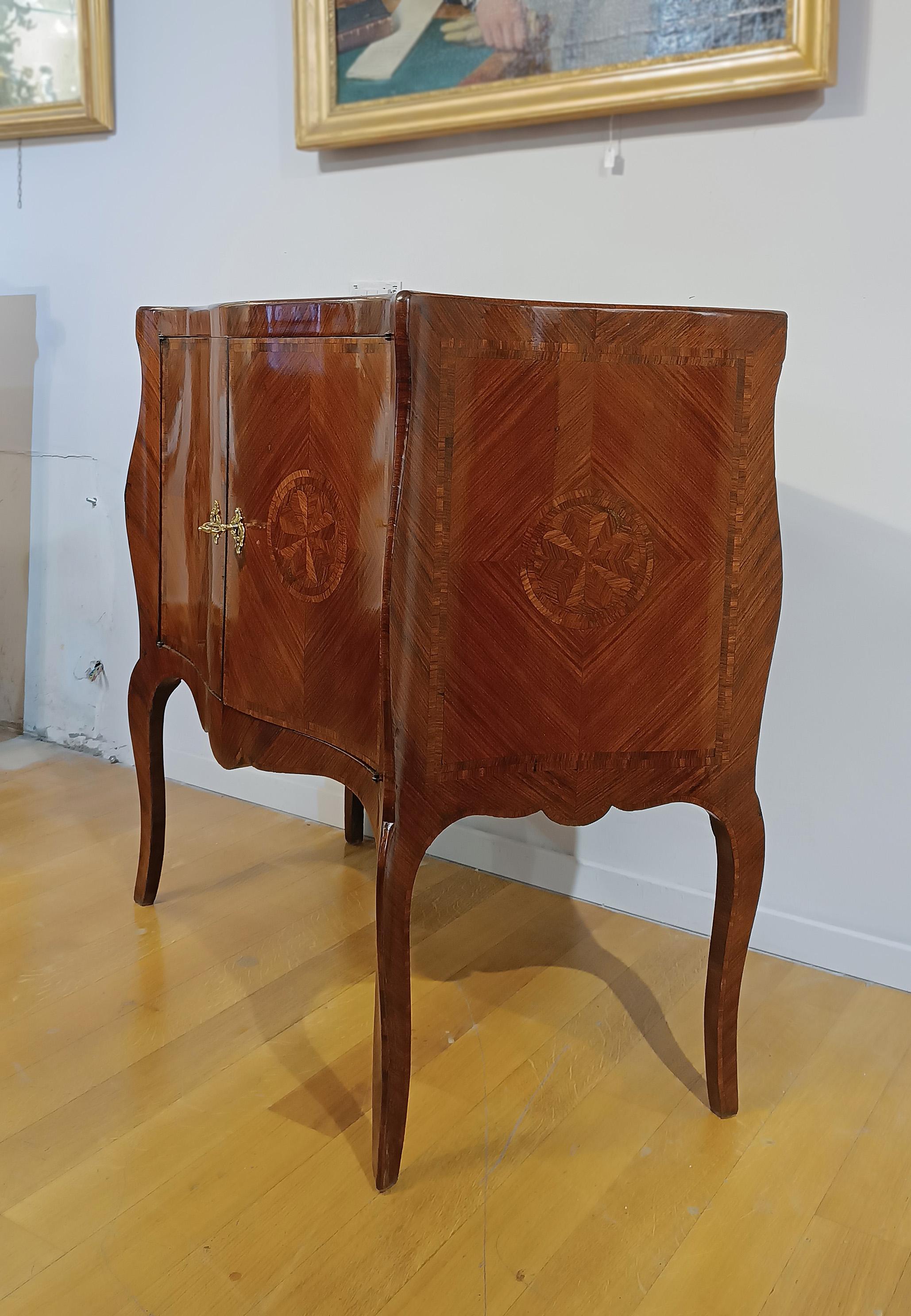 Elegant small sideboard in poplar wood, hand-carved and veneered in walnut. The wavy front and sides give a touch of refinement to the piece of furniture, enriched by semi-curved legs. To further enhance its elegance, there are inlays in fruit wood,