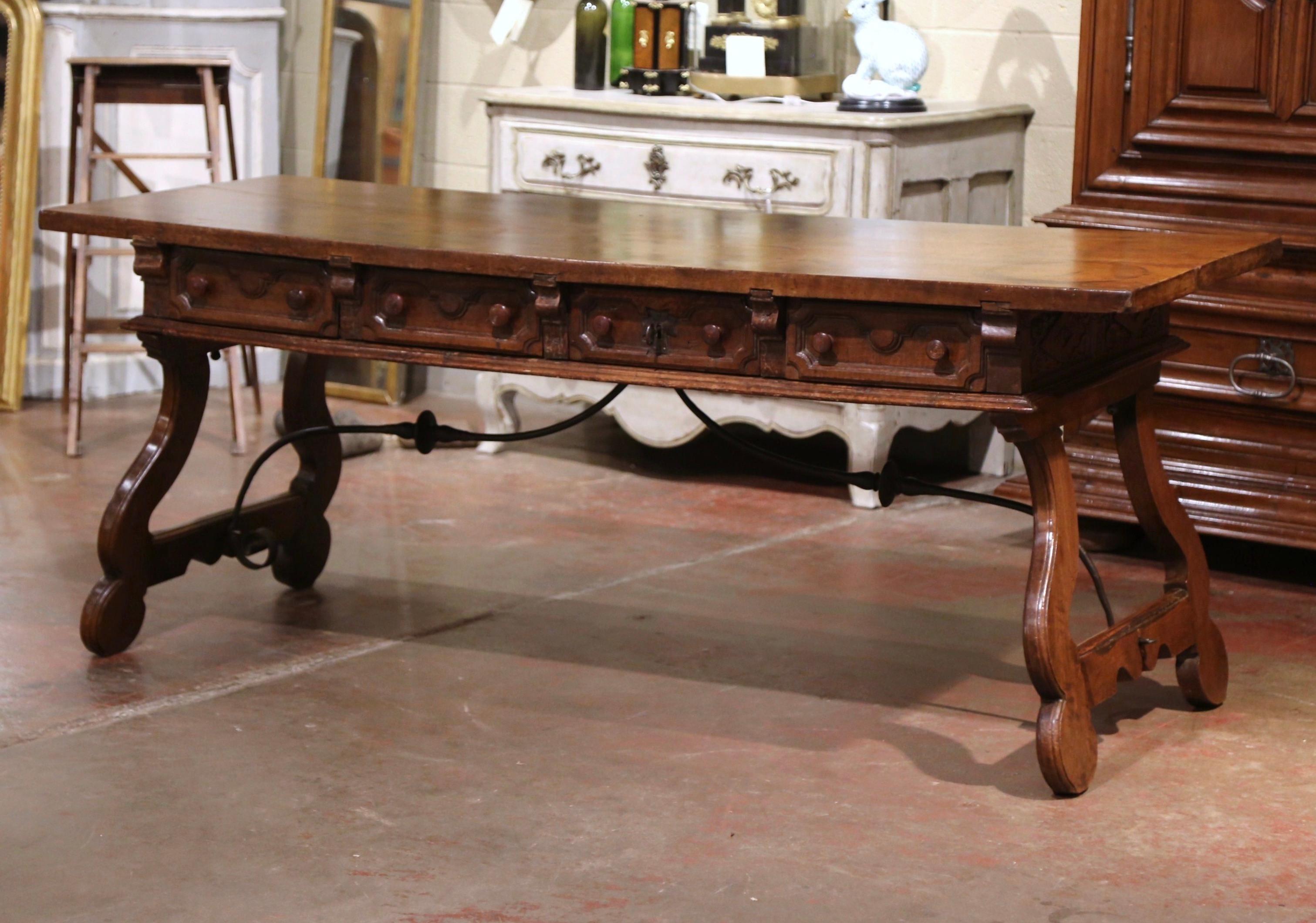 Add an elegant focal point to your study or library with this antique Spanish carved fruitwood desk. Carved in Spain circa 1750, the trestle table stands on two intricate carved legs, connected with a thick, forged wrought iron stretcher. The desk