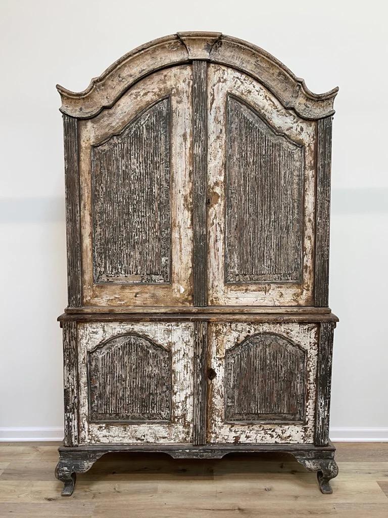 Swedish Rococo cabinet, Mid 18th Century Swedish Rococo cabinet in old paint, featuring the iconic curved lines of the Rococo style, with a pronounced bonnet top and shaped panels to the doors. The top section offers two large doors which enclose