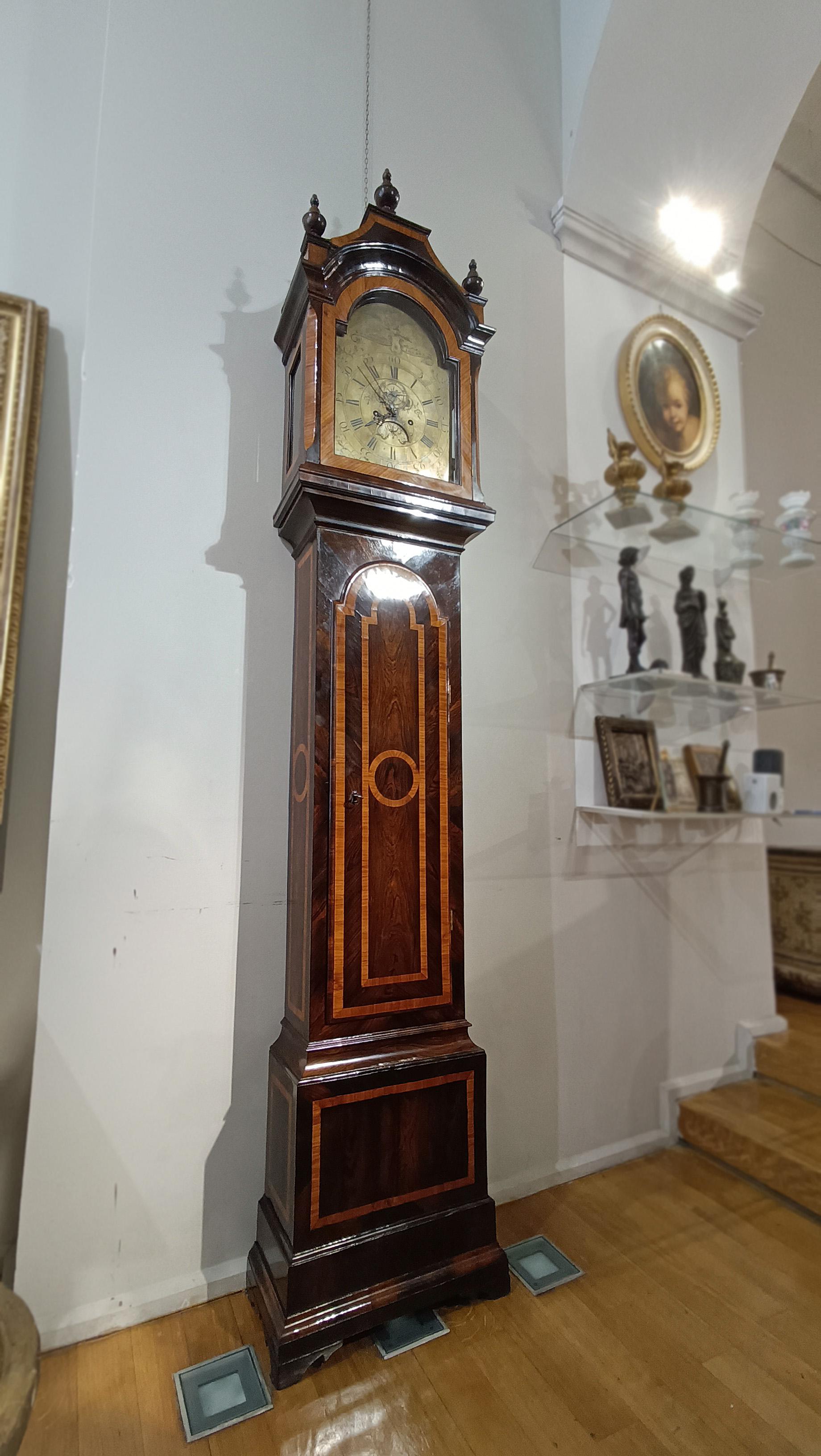 Elegant tower clock made of poplar and chestnut wood, covered in fruit wood. Made in Tuscany, the clock reflects the classic style of the mid-18th century, when the mechanisms were purchased in London and assembled according to Tuscan taste. The