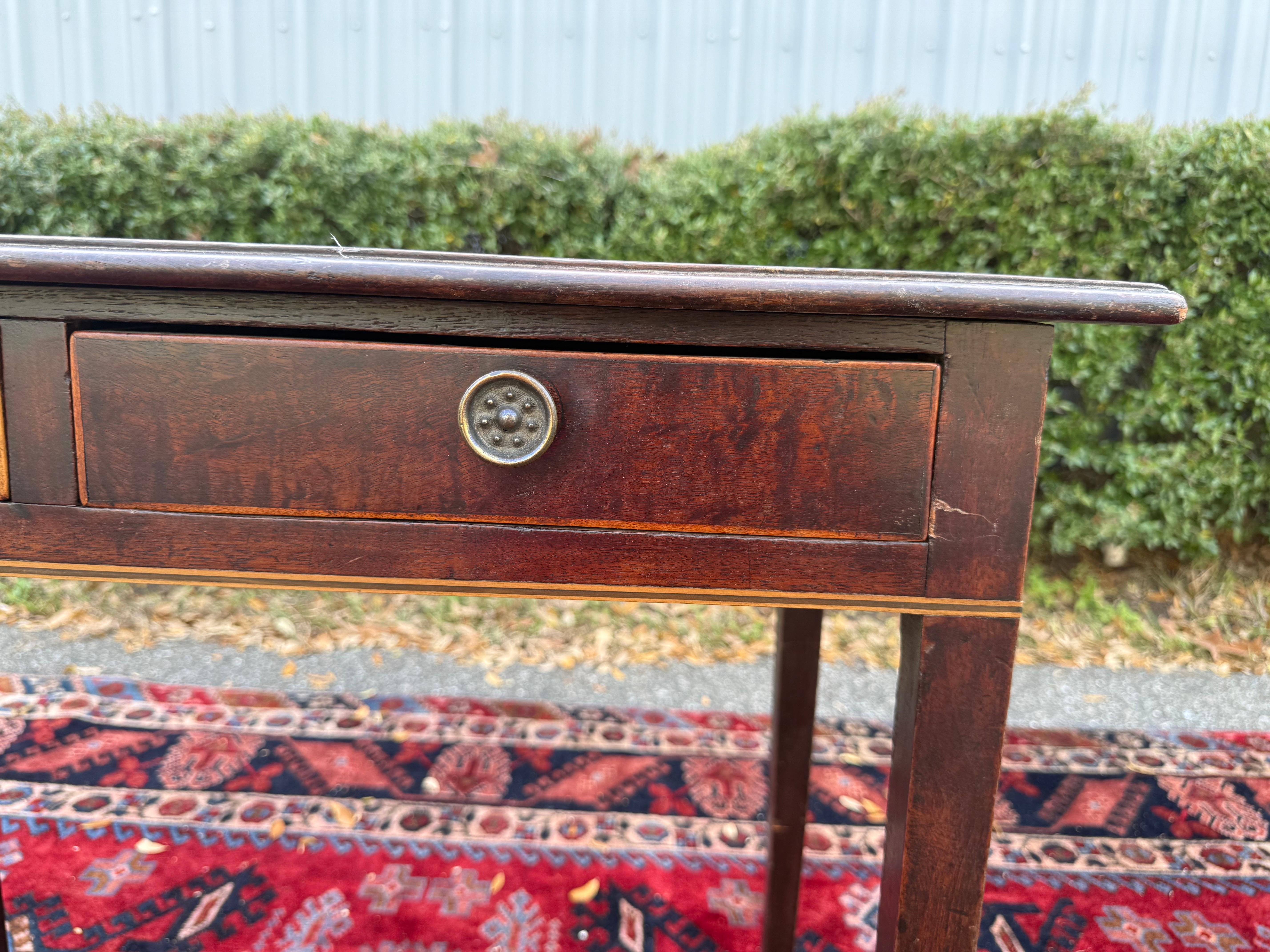 This handsome English mahogany server, c. 1850, features a narrow, rectangular surface over an apron outfitted with 2 drawers having beautiful hardware. The whole rests upon square tapering legs. The proportions of this server would work well as a