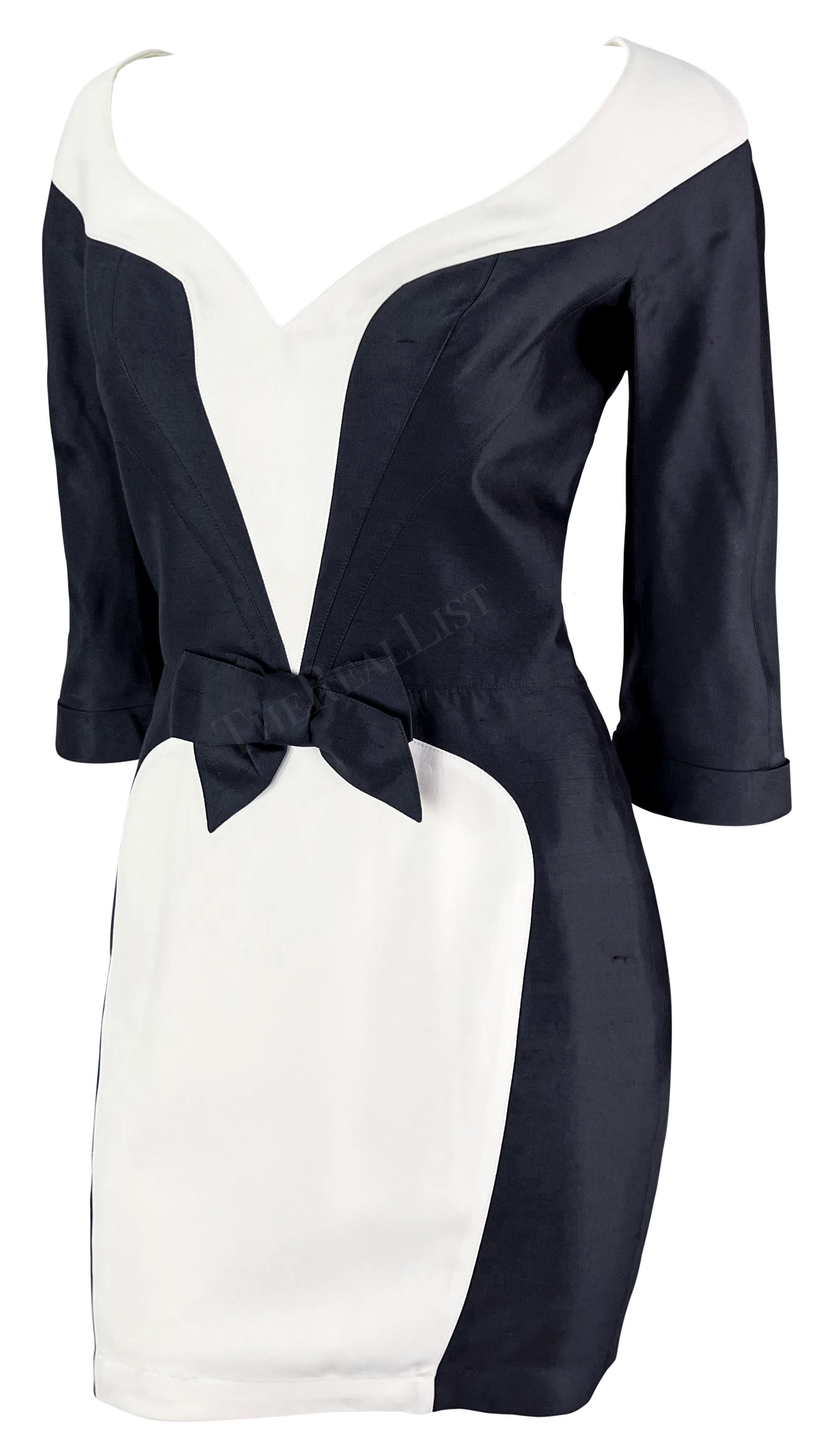 Sie präsentiert ein schickes schwarz-weißes Minikleid von Thierry Mugler. Dieses Kleid aus der Mitte der 1990er Jahre ist in Schwarz und Weiß gehalten. Das Kleid hat einen V-Ausschnitt, der sich spielerisch um die Brust legt, angeschnittene Ärmel