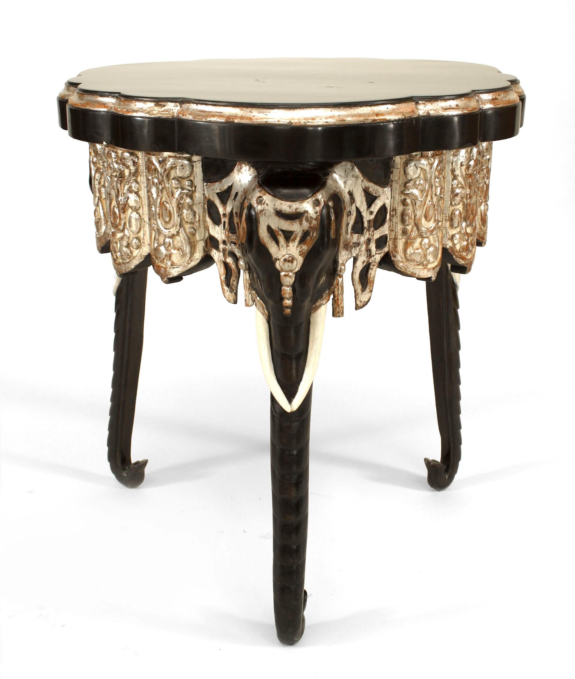 English Regency (Anglo-Indian) (Mid-19th Century) style black lacquered and parcel silver gilt carved and trimmed side table with scallop design edged top on 3 elephant mask legs.
