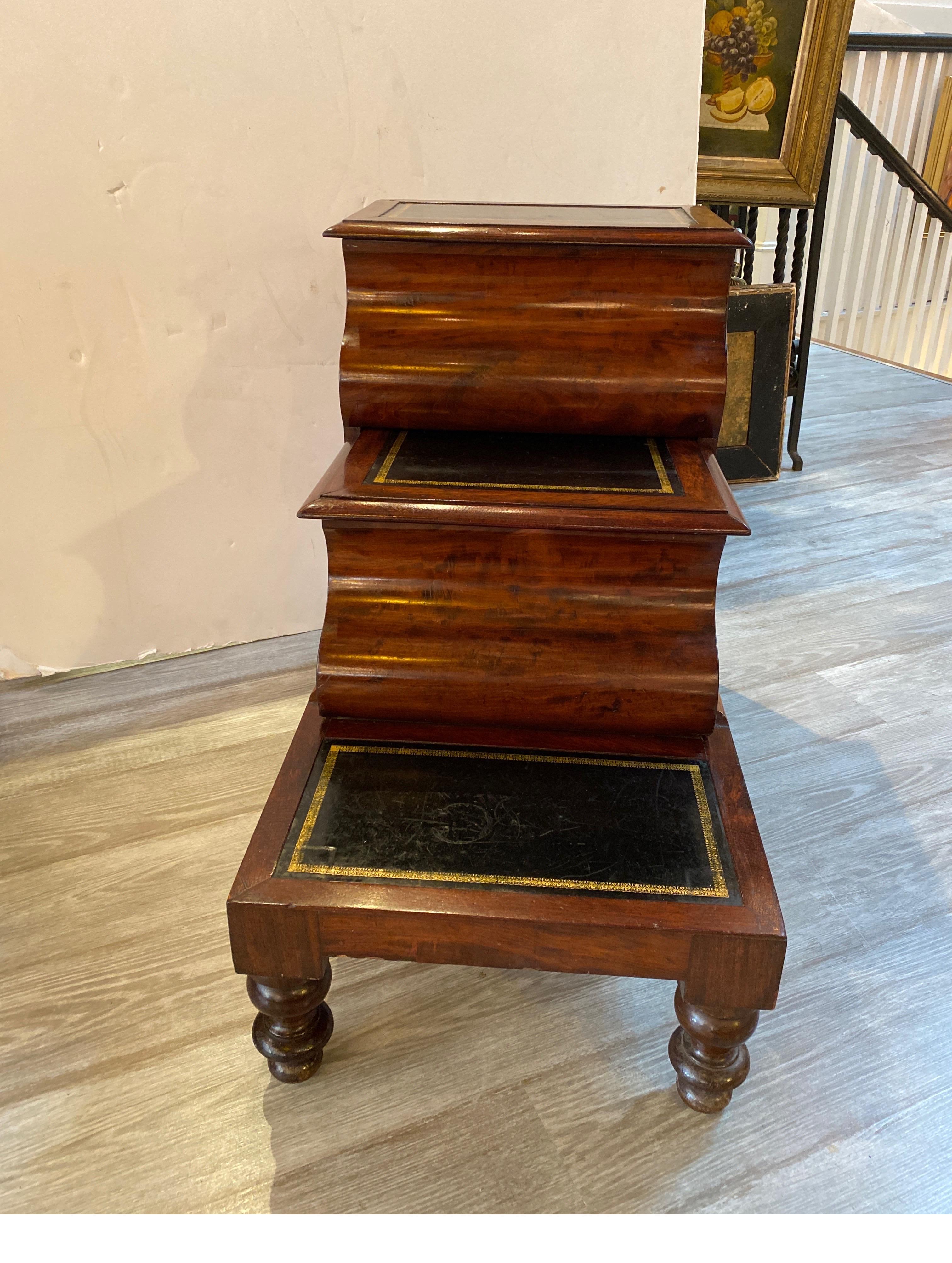 Circa 1840 American Empire mahogany library steps. The shaped steps with leather tops. The center step slides out to reveal a storage compartment.