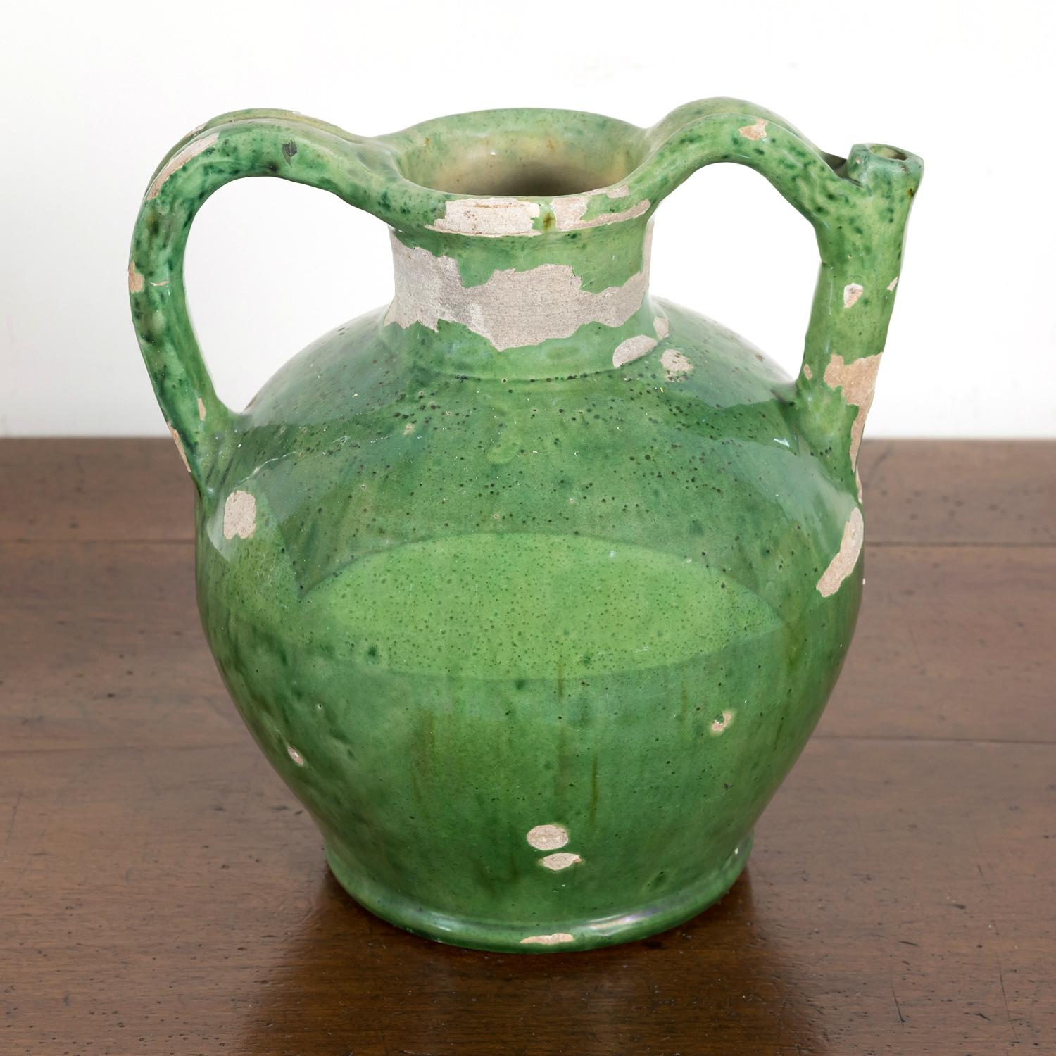 A fantastic mid-19th century French cruche orjol or water jug from the Languedoc region in southwest France, having a rare and luminous green glaze and two beautifully arched handles that rise above the opening with the spout formed into the handle