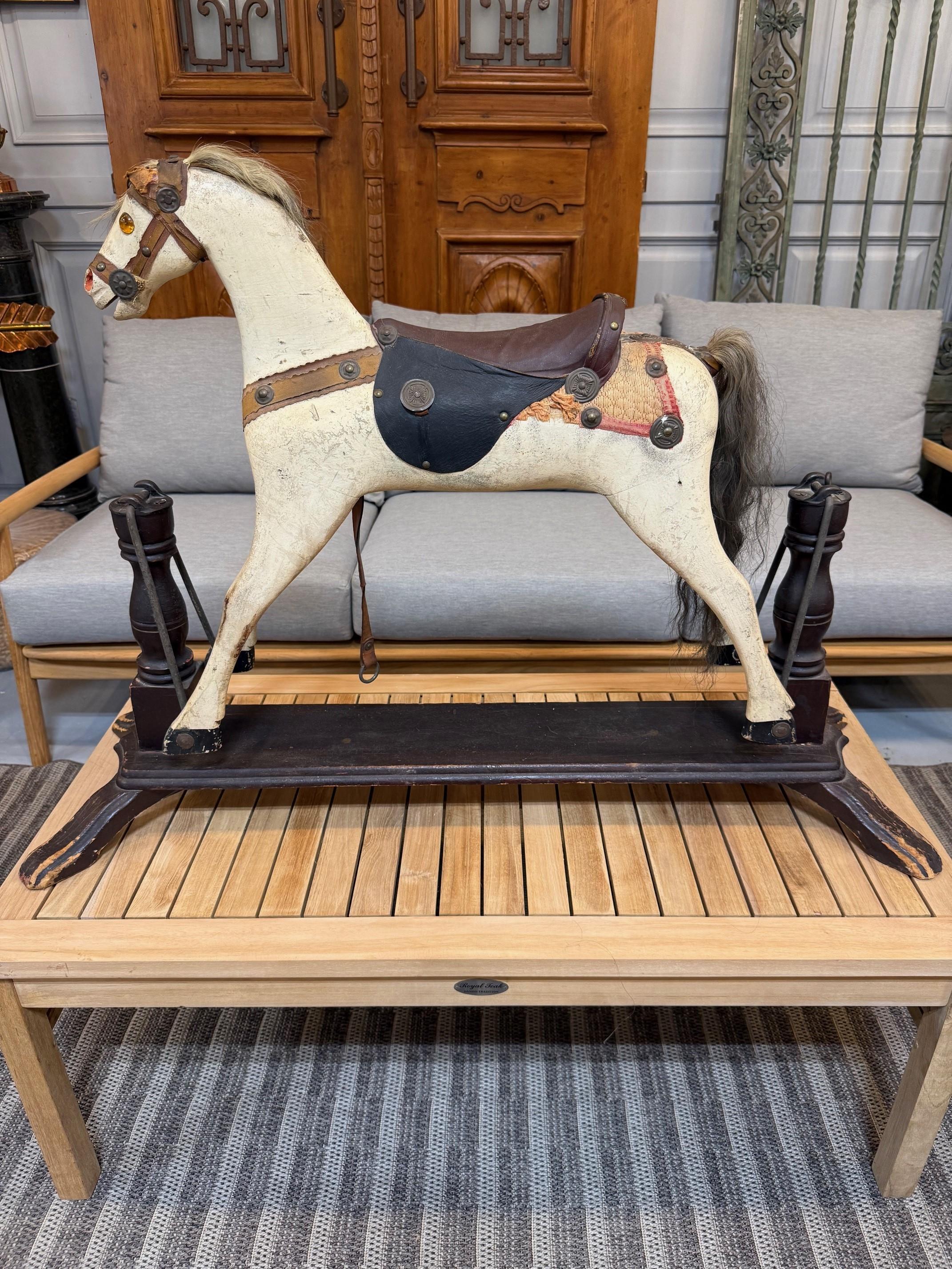 Maravilloso caballo balancín de madera de trabajo popular de mediados del siglo XIX, pintado con pintura blanca temprana, con ojos de cristal {falta uno}, crin y cola de pelo auténtico, silla de montar de cuero sobre un armazón de madera. Data de