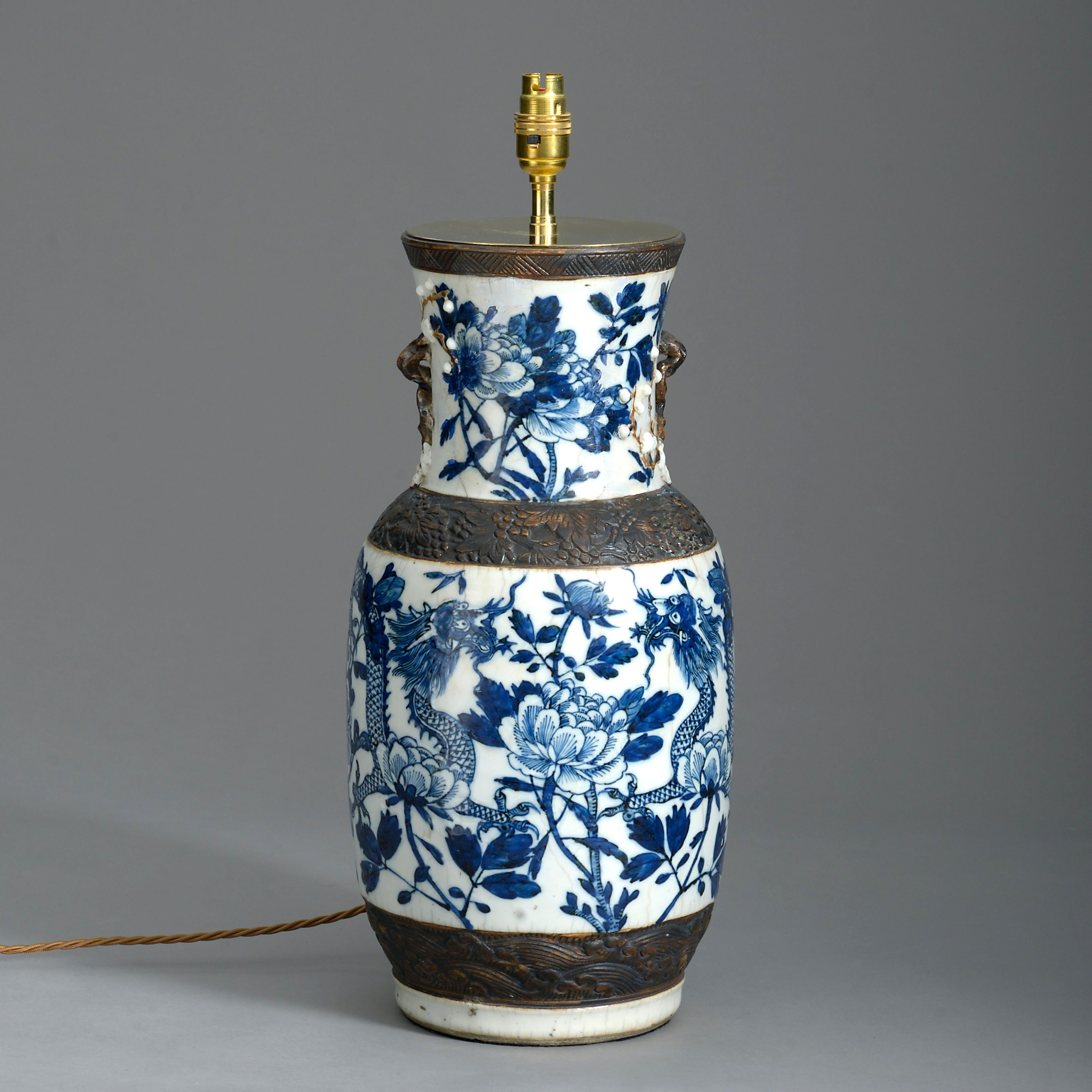 A mid-19th century vase of good scale, decorated with dragons in blue and white glazes, having faux bronze handles, rim, collar and base. Now mounted as a lamp base.