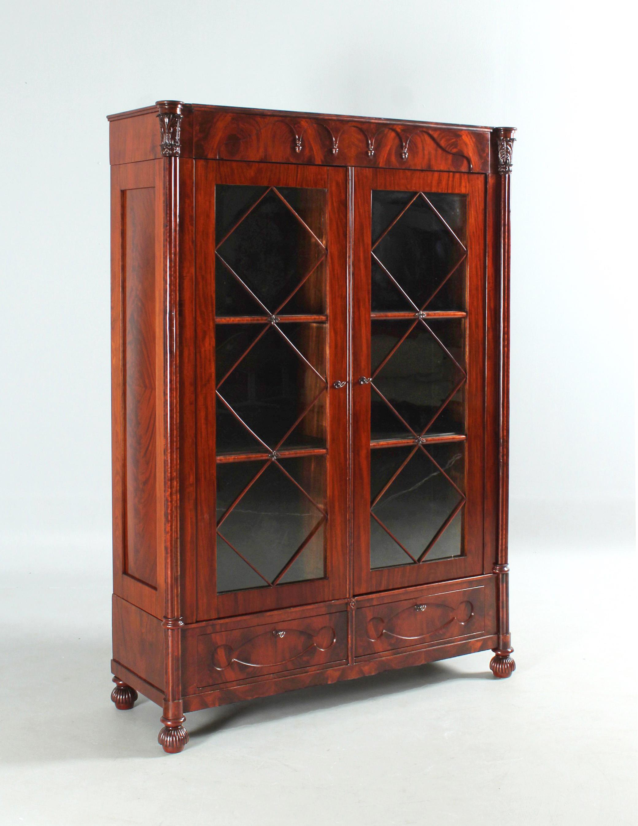 Antique bookcase

North Germany
Mahogany
middle 19th century

Dimensions: H x W x D: 198 x 138 x 49 cm

Description:
Front glazed bookcase from the late Biedermeier era circa 1850-1860.

Body standing on carved round feet.
At the front we see two