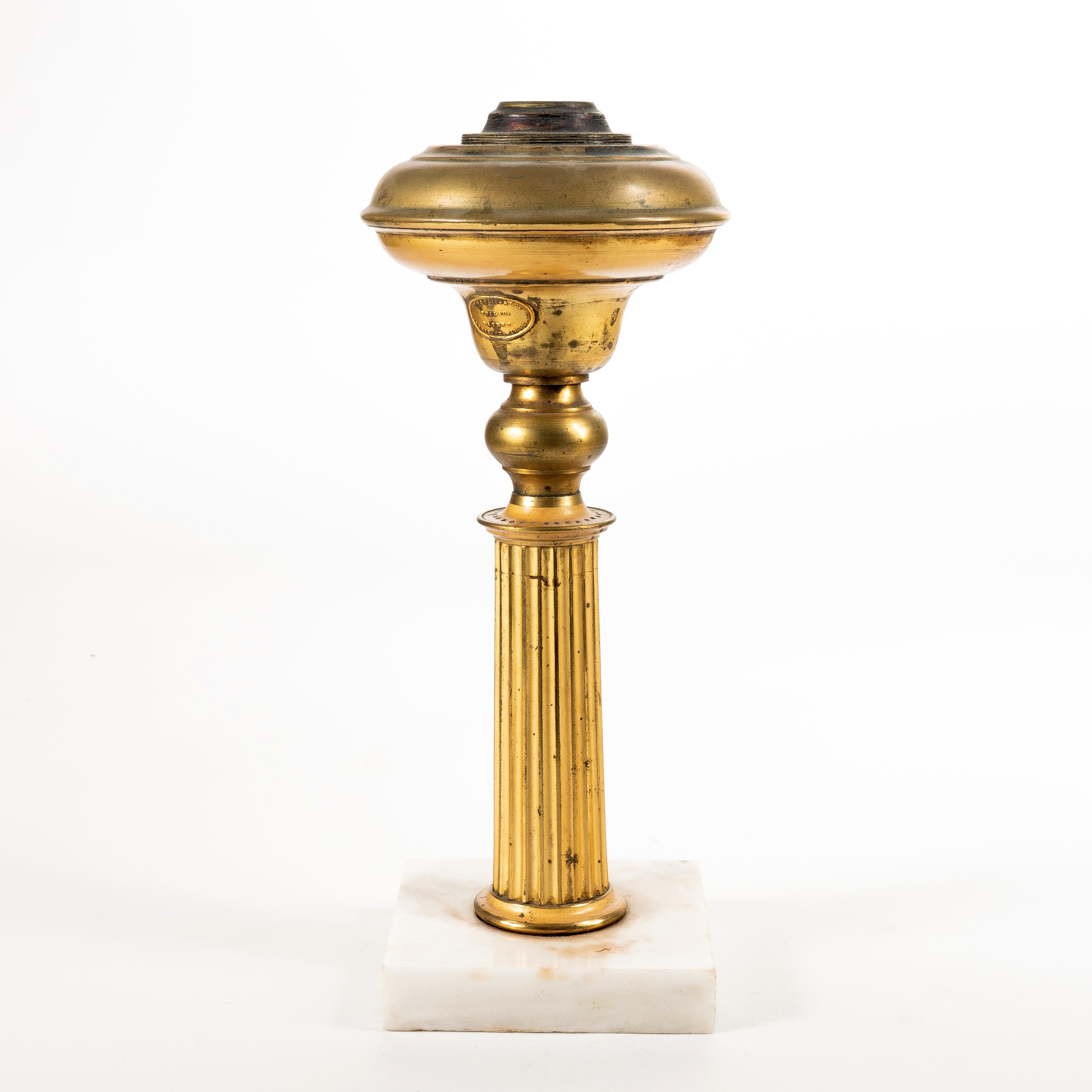 Fluted brass doric column astral lamp on a white marble base with compressed ball neck supporting a pear shaped font. The lamp retains its original gilt lacquer finish.
American, Philadelphia, 1843.