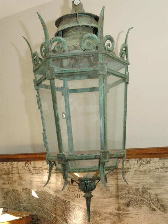 Mid 19th-century English hallway, foyer, or patio lantern with a hexagonal shape, verdigris bronze framework and glass siding. Crowned with the spikes of an upside-down rustic fleur de lis motif and offset by the spoke of a finial base, the piece