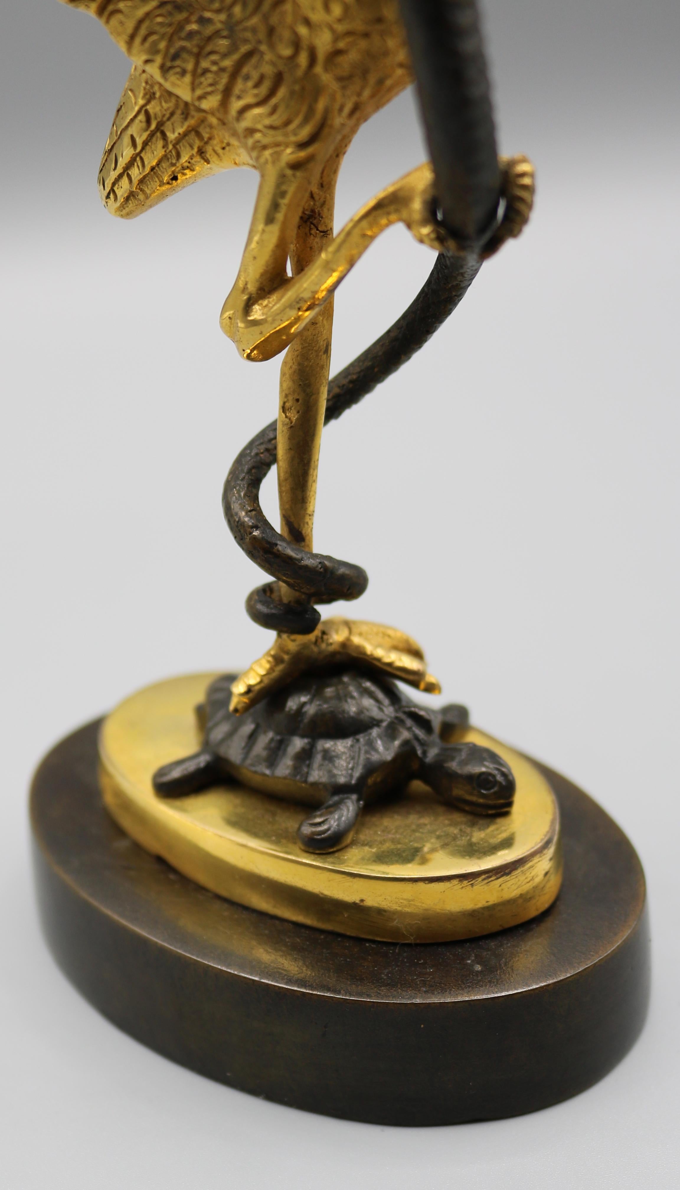 An unusual pair of mid-19th century bronze and ormolu candlesticks having leaf-moulded nozzles held by serpents and storks standing on turtles, supported on oval stepped plinth.