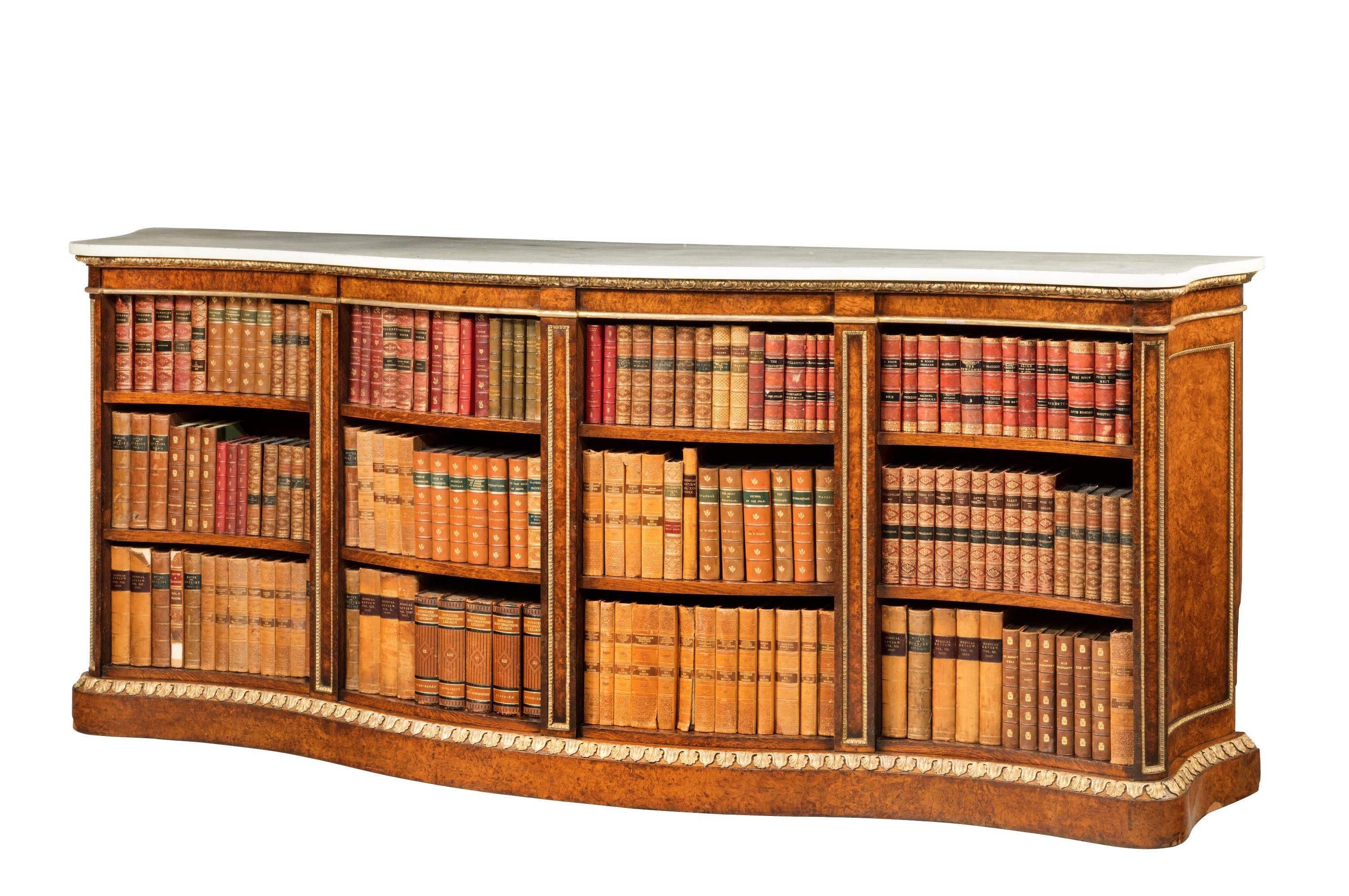 A rare mid-19th century burr oak open bookcase of serpentine form retaining the original white shaped marble top. The carcass enriched with gilded decoration. Ex Lotherton Hall, the family seat of the Gascoigne family, which is now a museum.