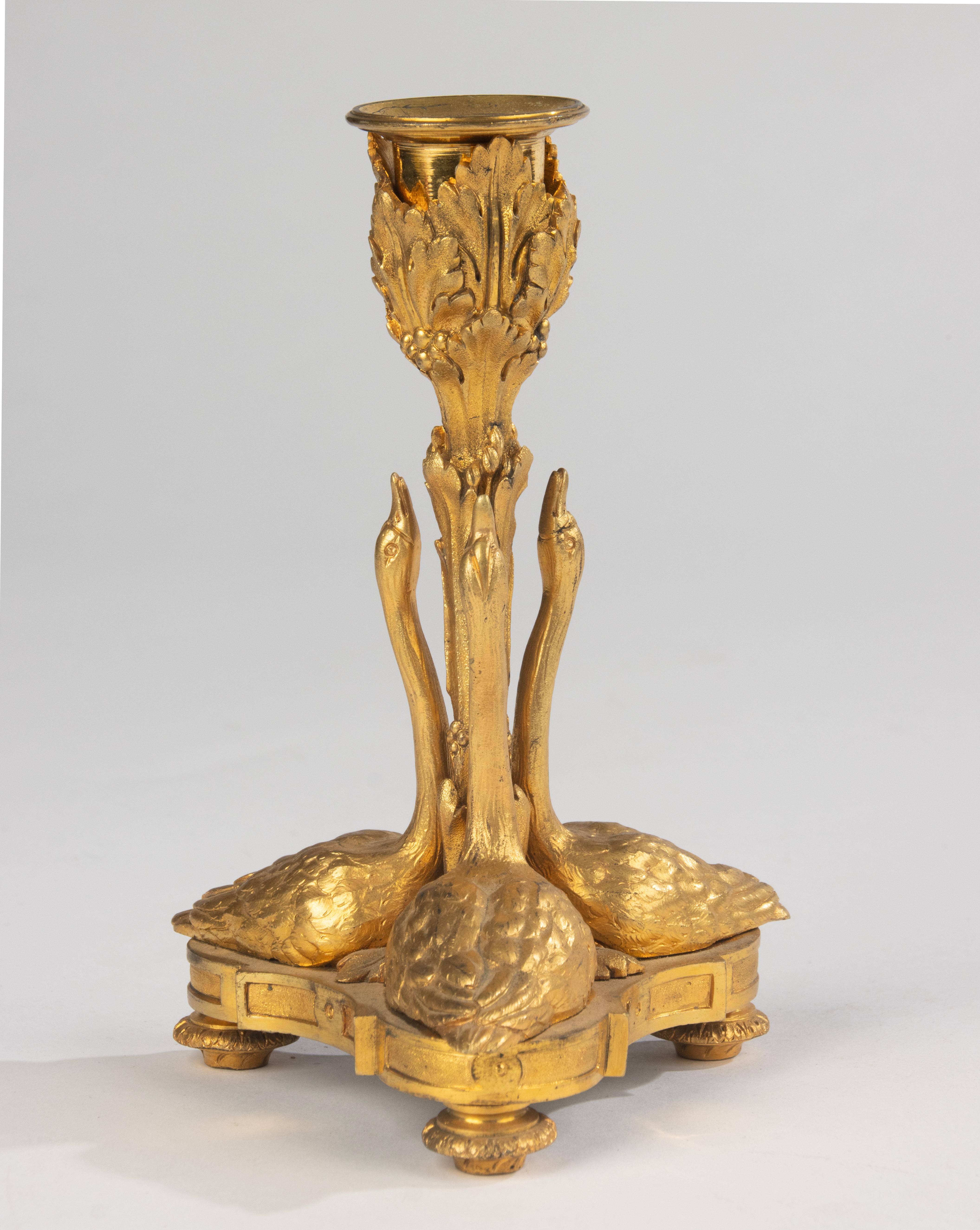 Refinado candelabro francés de bronce ormolu, mediados del siglo XIX, finamente detallado y bellamente fundido. La base está formada por tres cisnes esculpidos, cuyos largos cuellos se elevan graciosamente para sostener el candelabro, decorado con