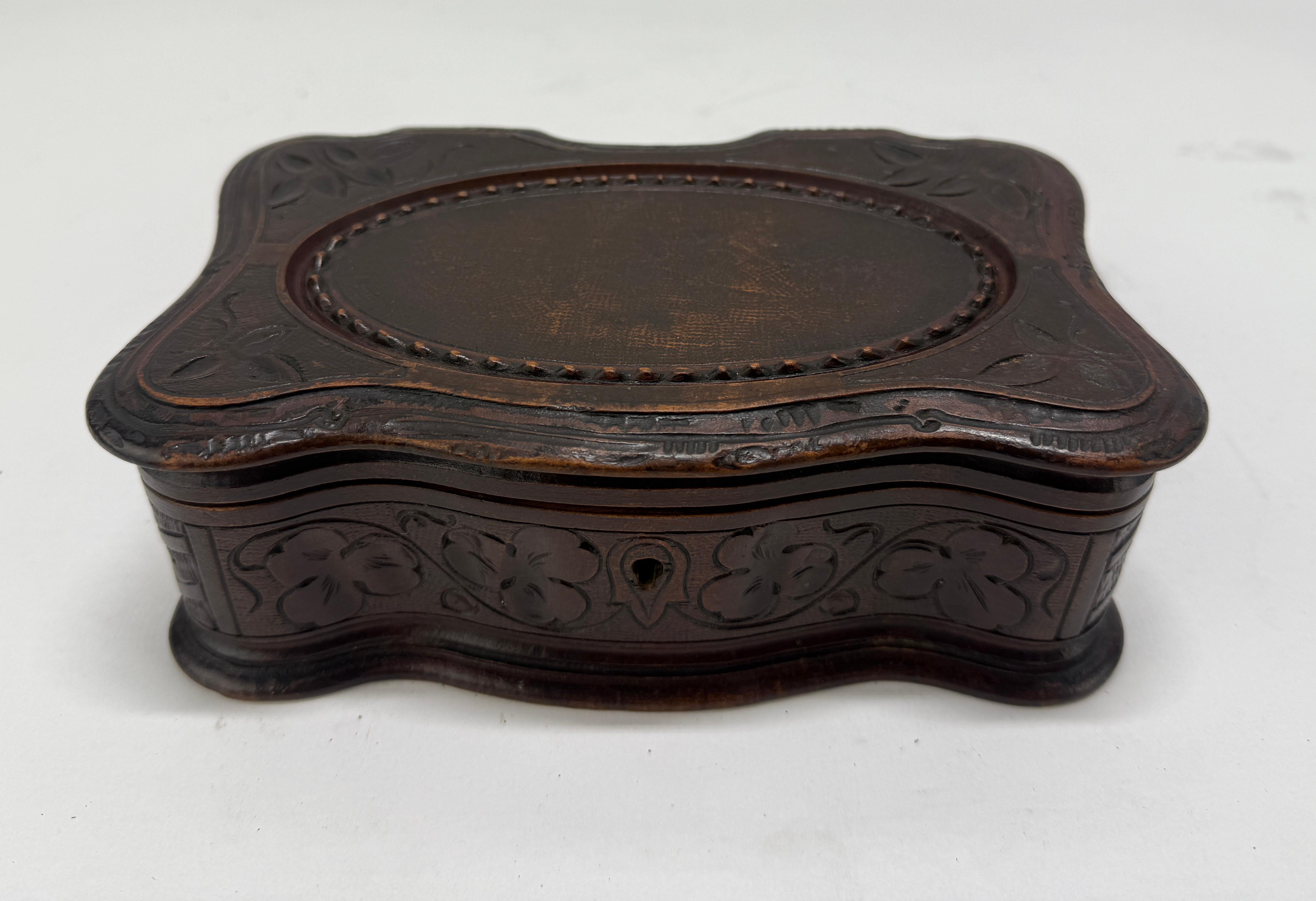 Boîte à bijoux ou à bibelots en noyer finement sculpté, milieu du 19e siècle, probablement d'origine suisse ou de la Forêt-Noire. La forme rectangulaire serpentine présente un contour rococo curviligne avec des bords festonnés, le sommet étant