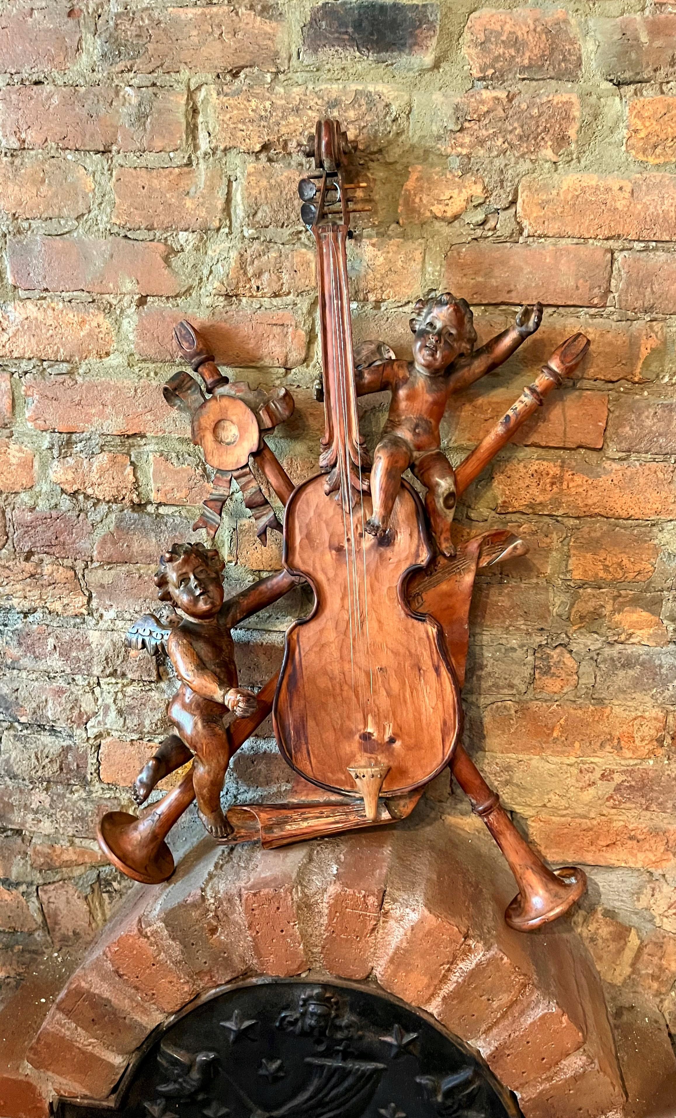Possibly a Grand Tour Souvenir or remnant .A carved  wall trophy allegory to music., possibly part of boiserie and later configured to present. Two cherubs or putti in ascension among violin, ribbon, and trumpets. Mixed woods, pine and