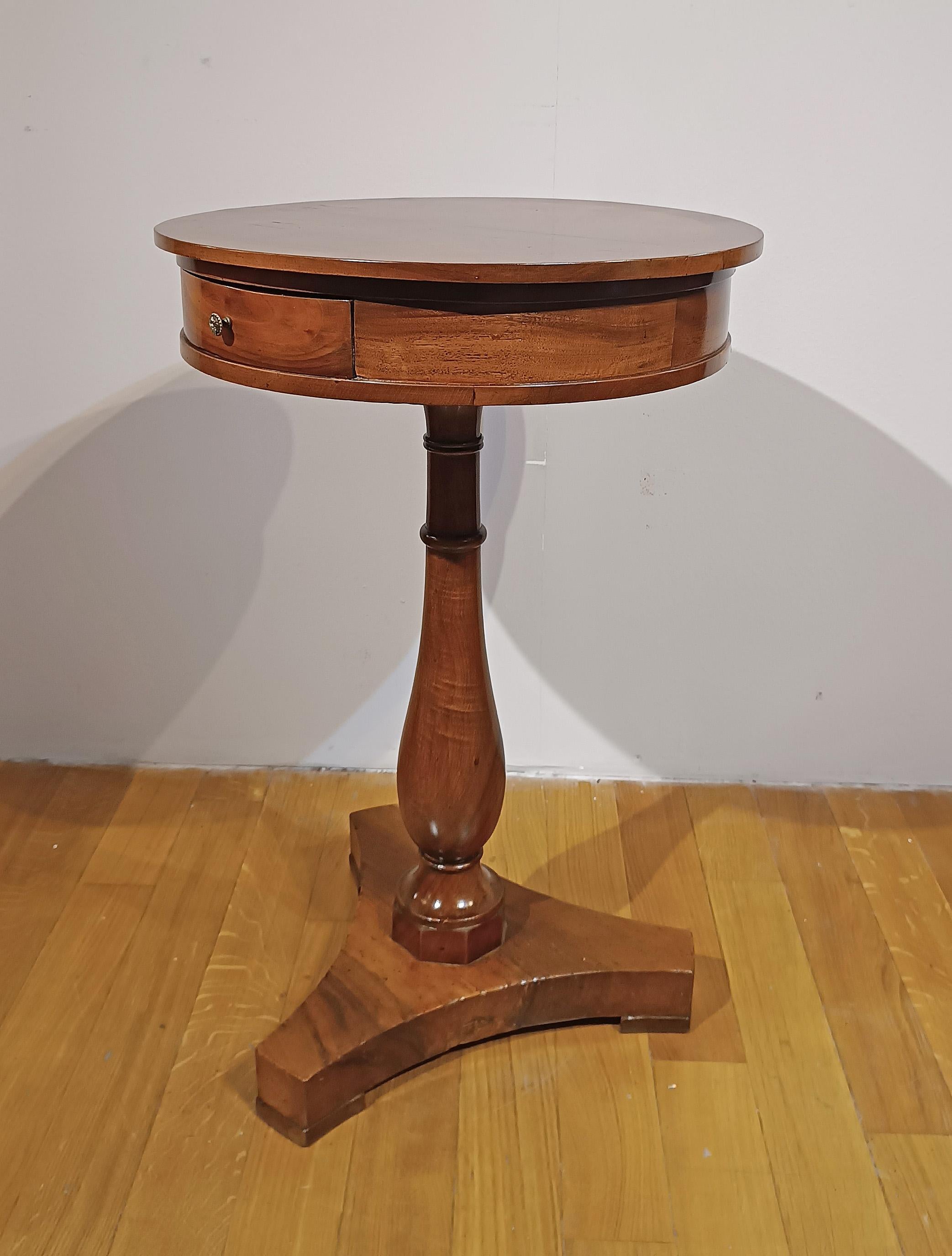 Refined coffee table veneered in cherry and walnut. Its central leg, turned from solid walnut, stands out for its elegance, with a triangular base completing its line. The round top is embellished with an external cherry band, lending an extra touch