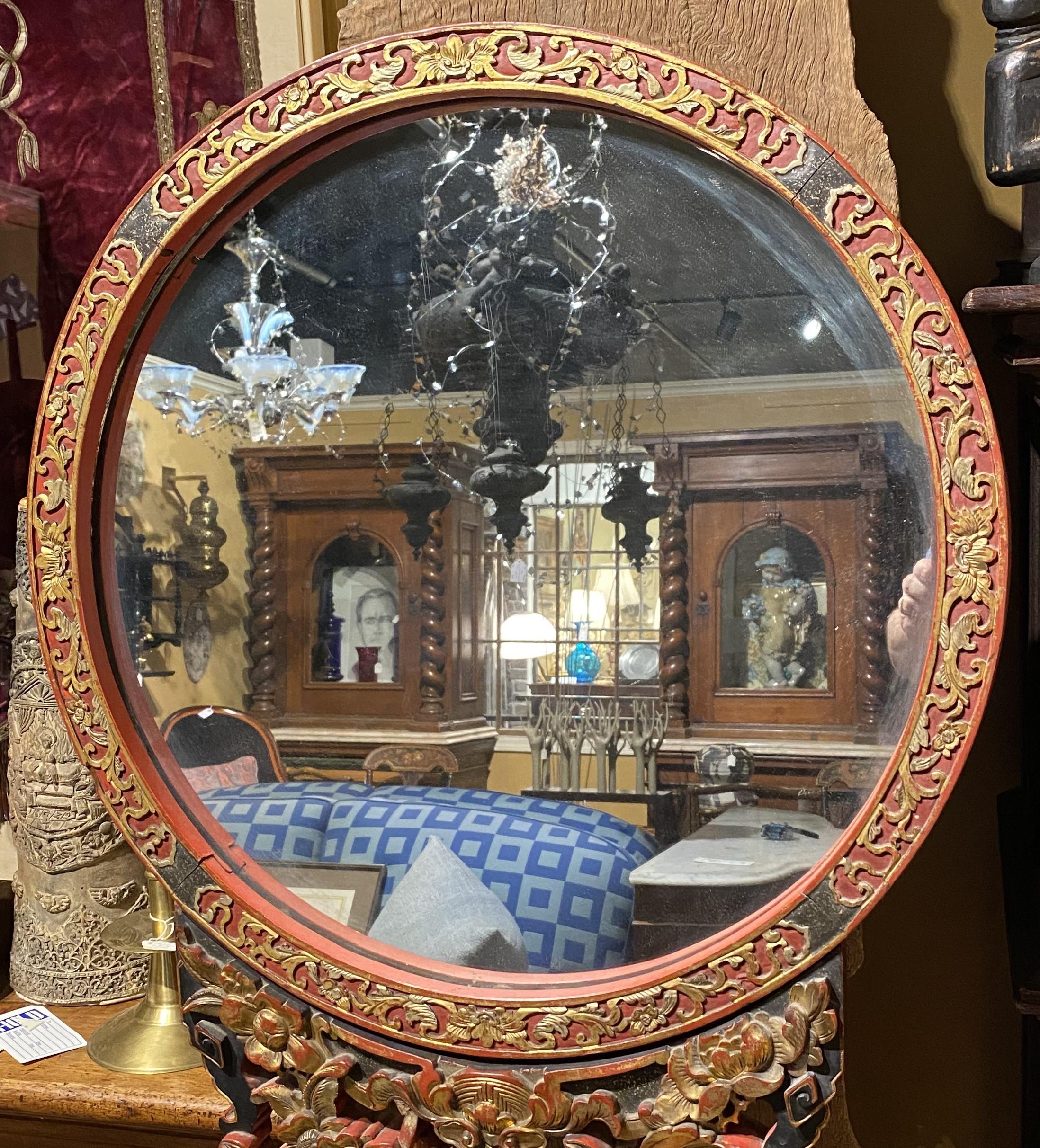 A beautifully carved 19th century Chinese round floor mirror with red gilt lacquer surround on a heavily relief carved stand with flowers and figures, mounted on a rectangular stand with pierce carved skirt and short cabriole legs. The stand is peg