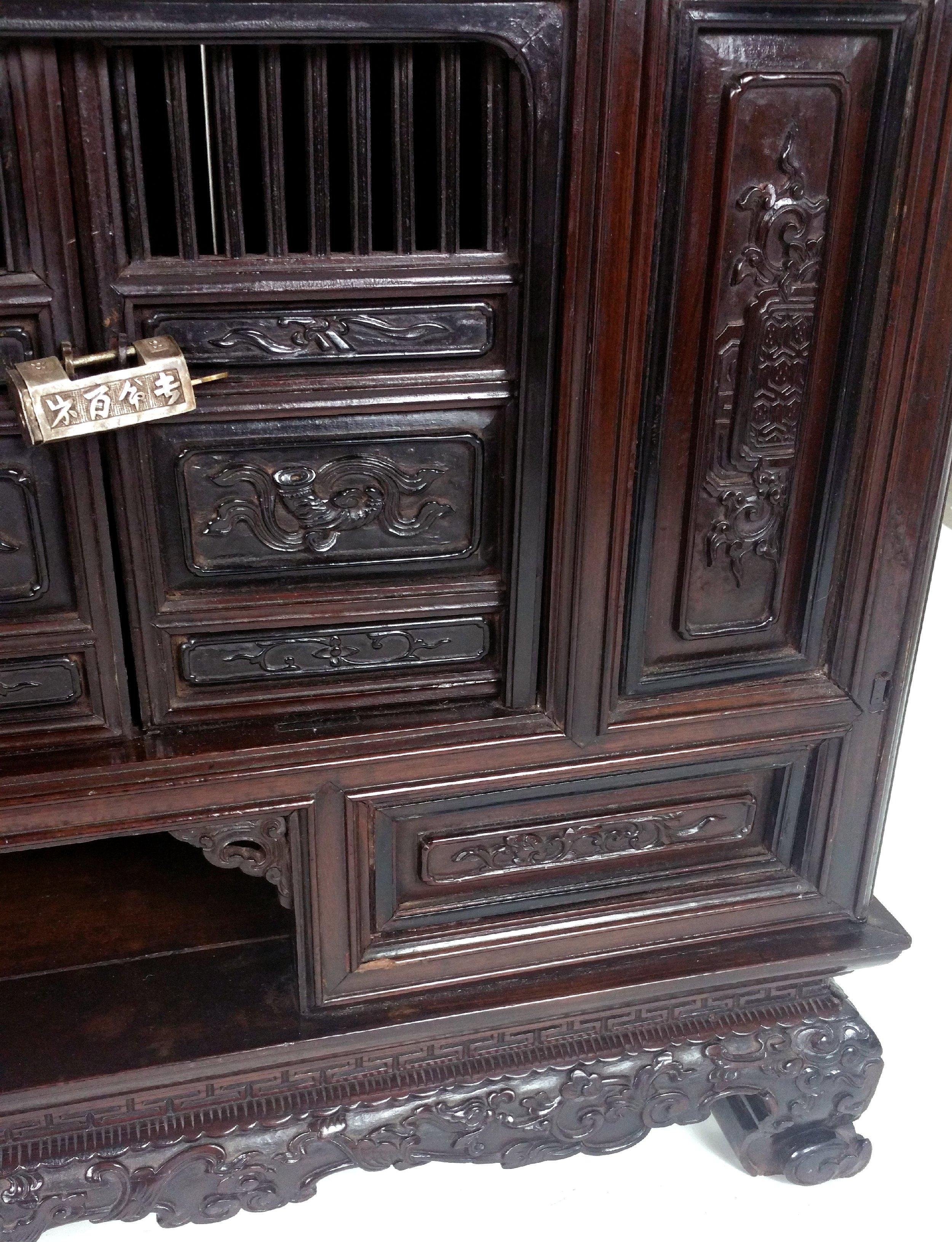 This beautiful mid-19th century. Chinese ornately carved side cabinet is set with a series of drawers and cupboards, with decorative silver locks. The sides are carved with precious objects and flowers and the chest stands on carved feet. The chest