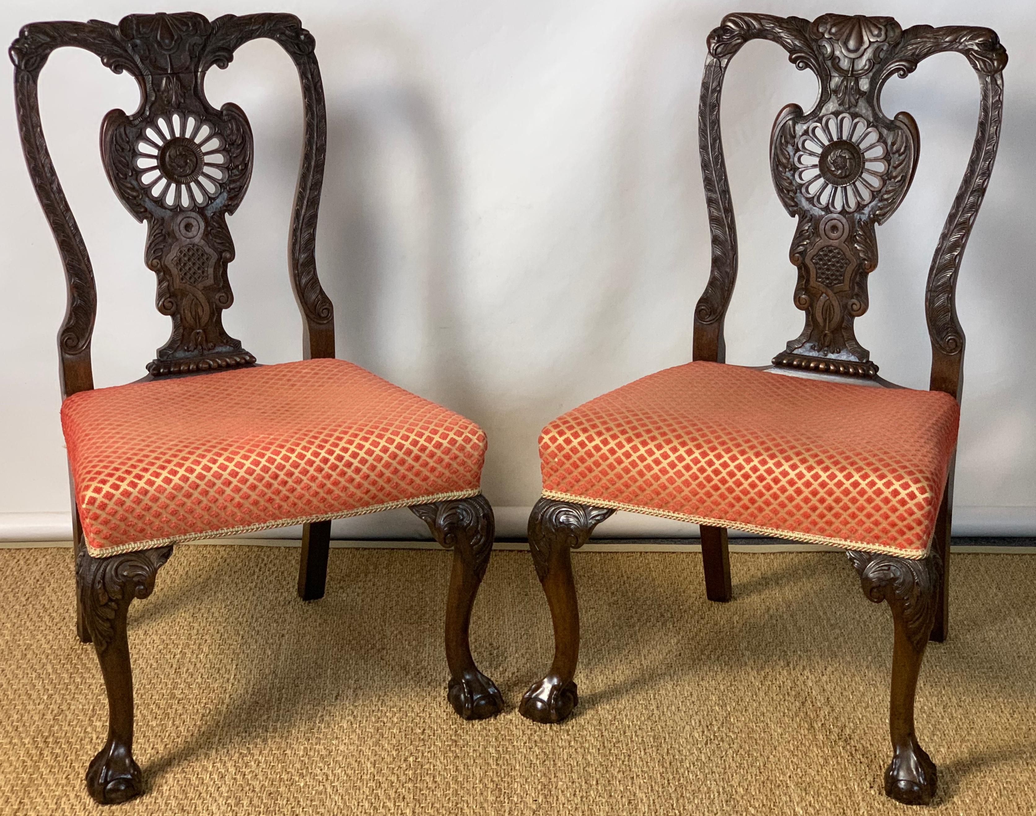 A fine pair of mid-19th century English elaborately carved Chippendale style mahogany side chairs upholstered in a coral and gold colored fabric.
