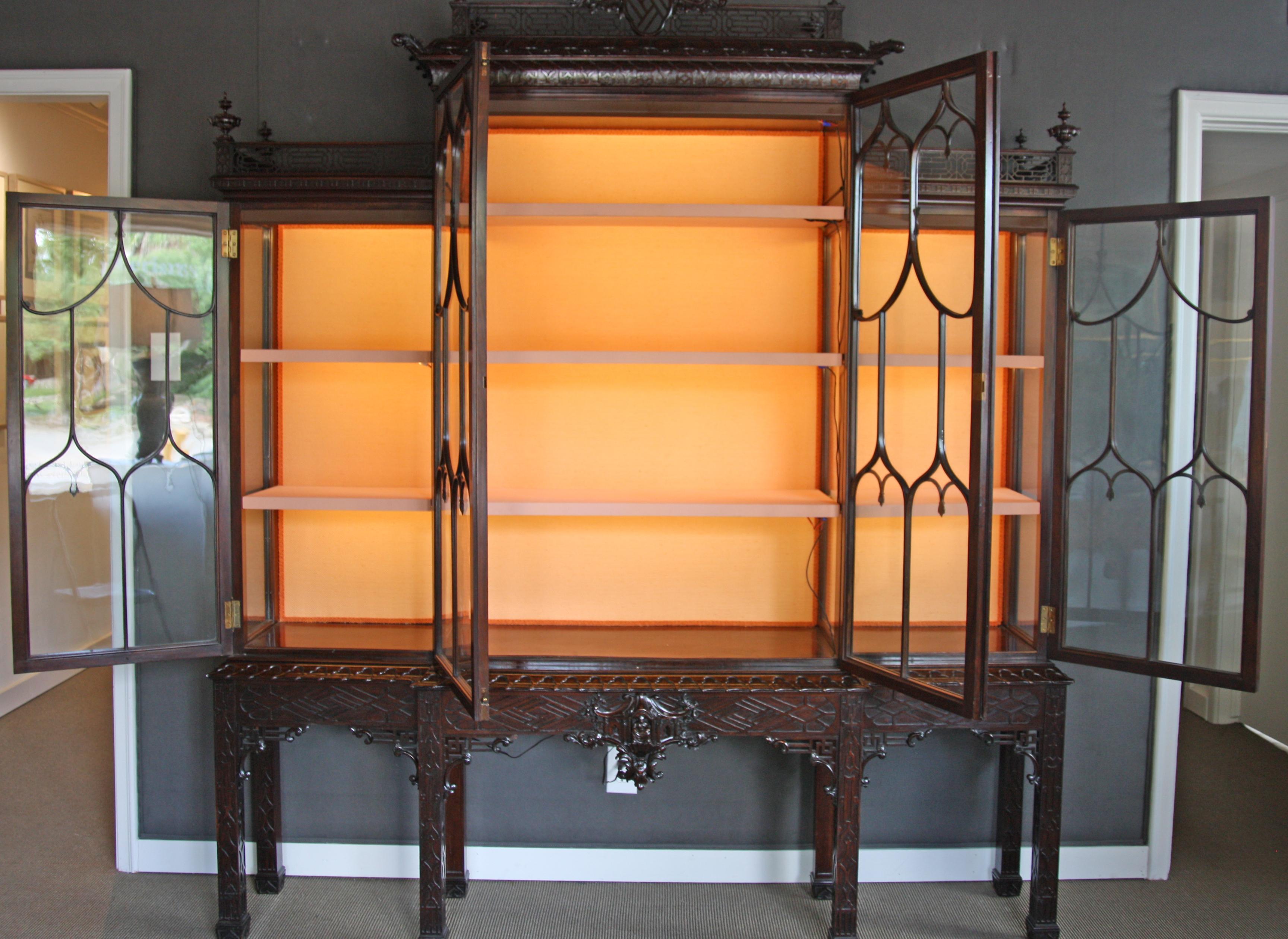 Mid-19th century china cabinet is constructed from mahogany in the style of Thomas Chippendale. The cabinet has a center breakfront section with two glazed doors each with 14 panes flanked by a section at each side, each with nine panes. The