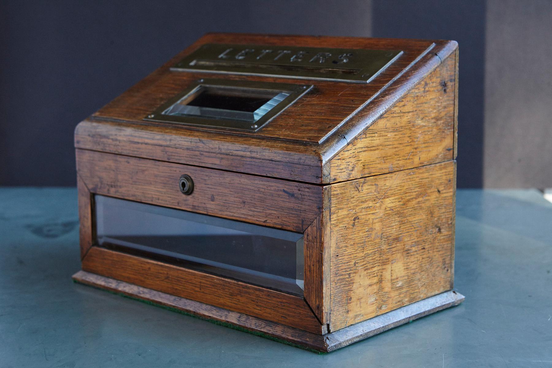 A mid-19th century country house desk top letter box, the oak body centred by a slope-front brass-mounted posting box titled 