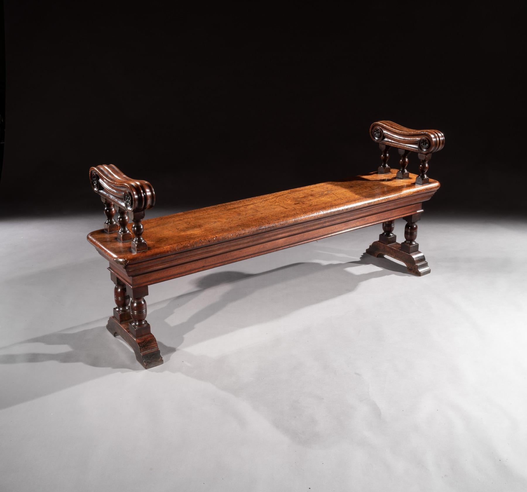 A wonderful mid-19th century country house walnut hall bench measuring 168cm long (65.5 inches) English circa 1850 an unusual model having beautiful oversized scrolled end supports with the original color and patination which is about as good as it