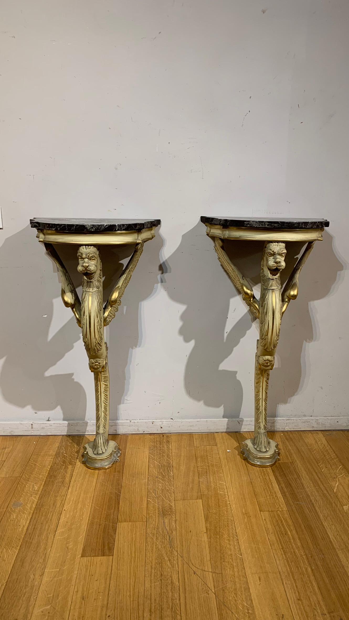 Beautiful pair of wall consoles supported by a winged fantastic animal with one leg made of carved and painted ivory-colored wood with pure gold leaf highlights.
The use of these particular griffins traces the creation of these two small but