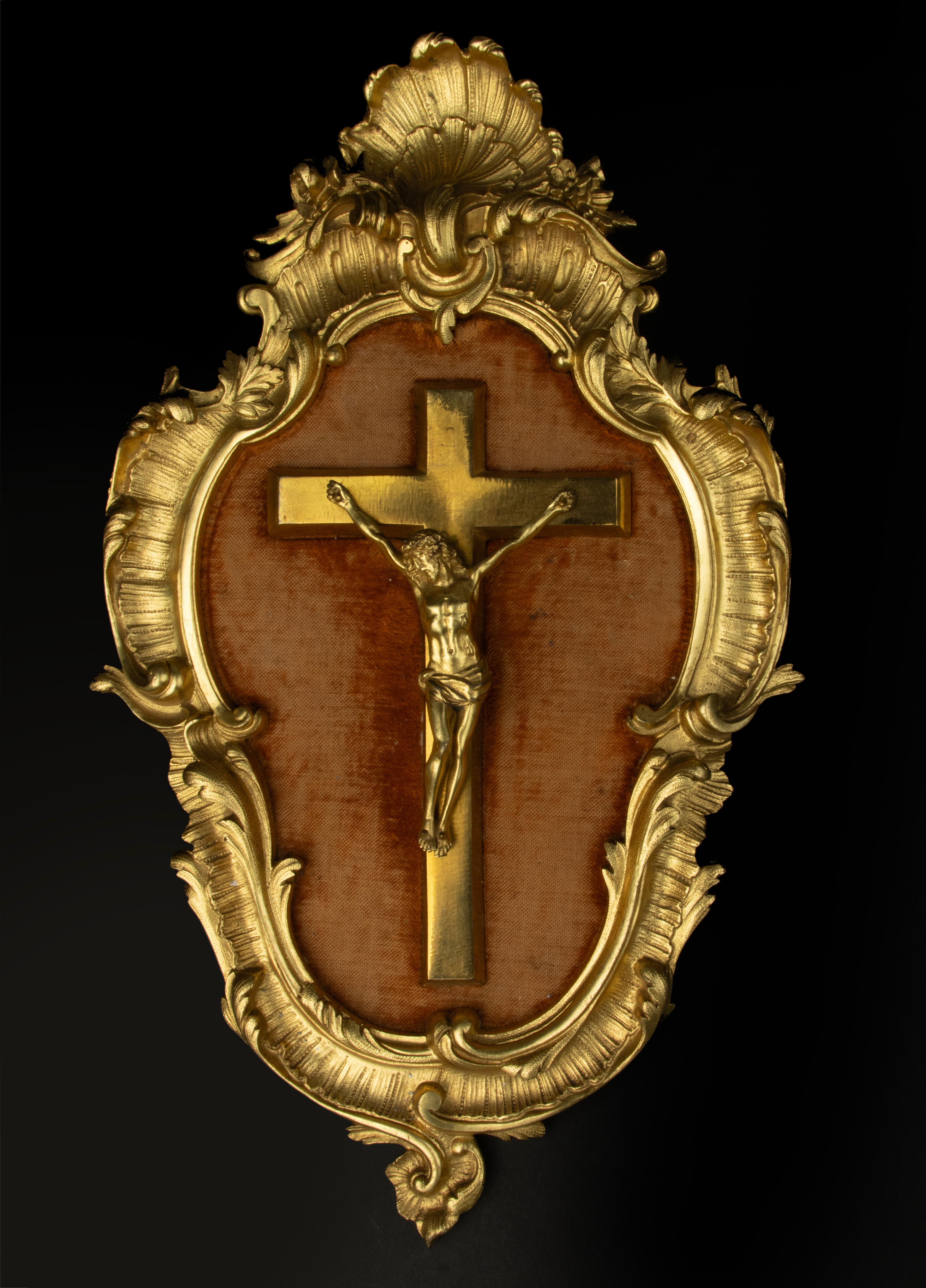 A refined antique wall plaque with a Jesus Christ crucifix. Made of ormolu gilded bronze. The cross is mounted on a red velvet panel. In a Rococo bronze rocaille frame. Gilding is in good condition. The velvet has some wear during age. 

Made in te