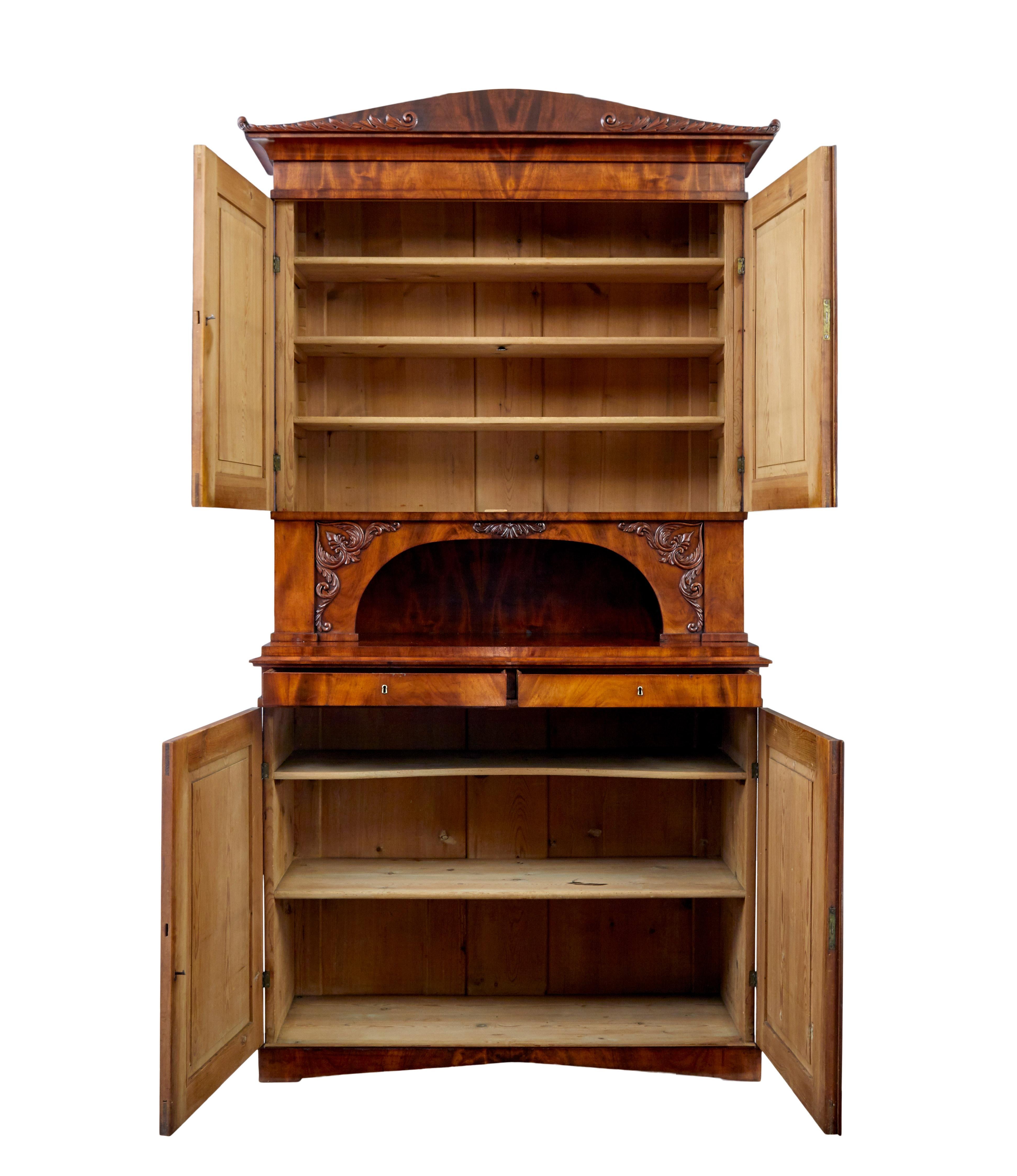 Good quality danish 2 part tall mahogany cabinet circa 1860.

Top section with scrolled cornice and applied swags, double doors with shaped panels open to reveal 3 adjustable pine shelves.  Below this an open display aperture with further applied