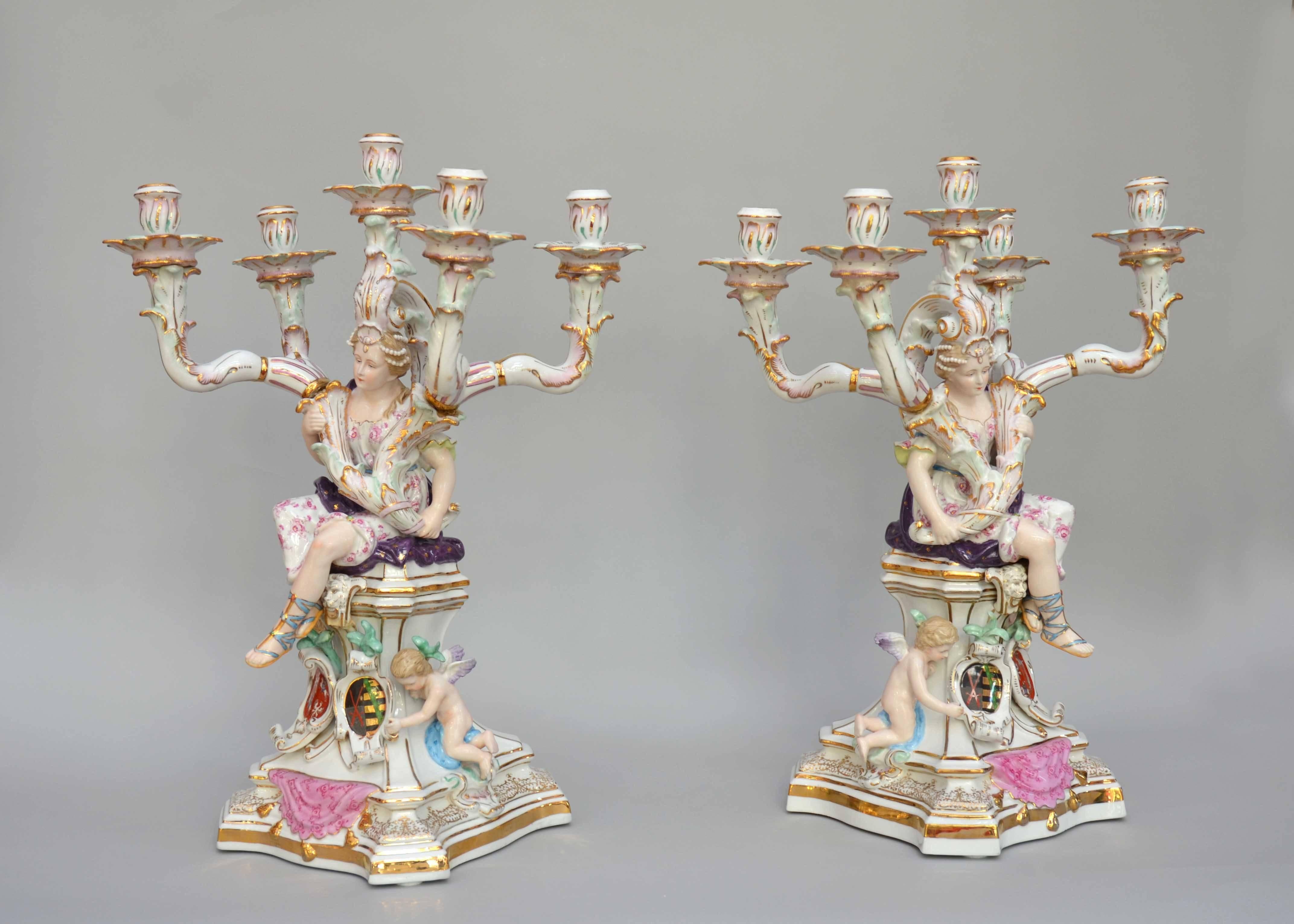 Pair of figural porcelain candlesticks with five branches. An elegant woman is holding the branches, at her feet children near shileds with armorial bearings. After the model of the Meissen manufactory, these are Dresden porcelain. Great condition