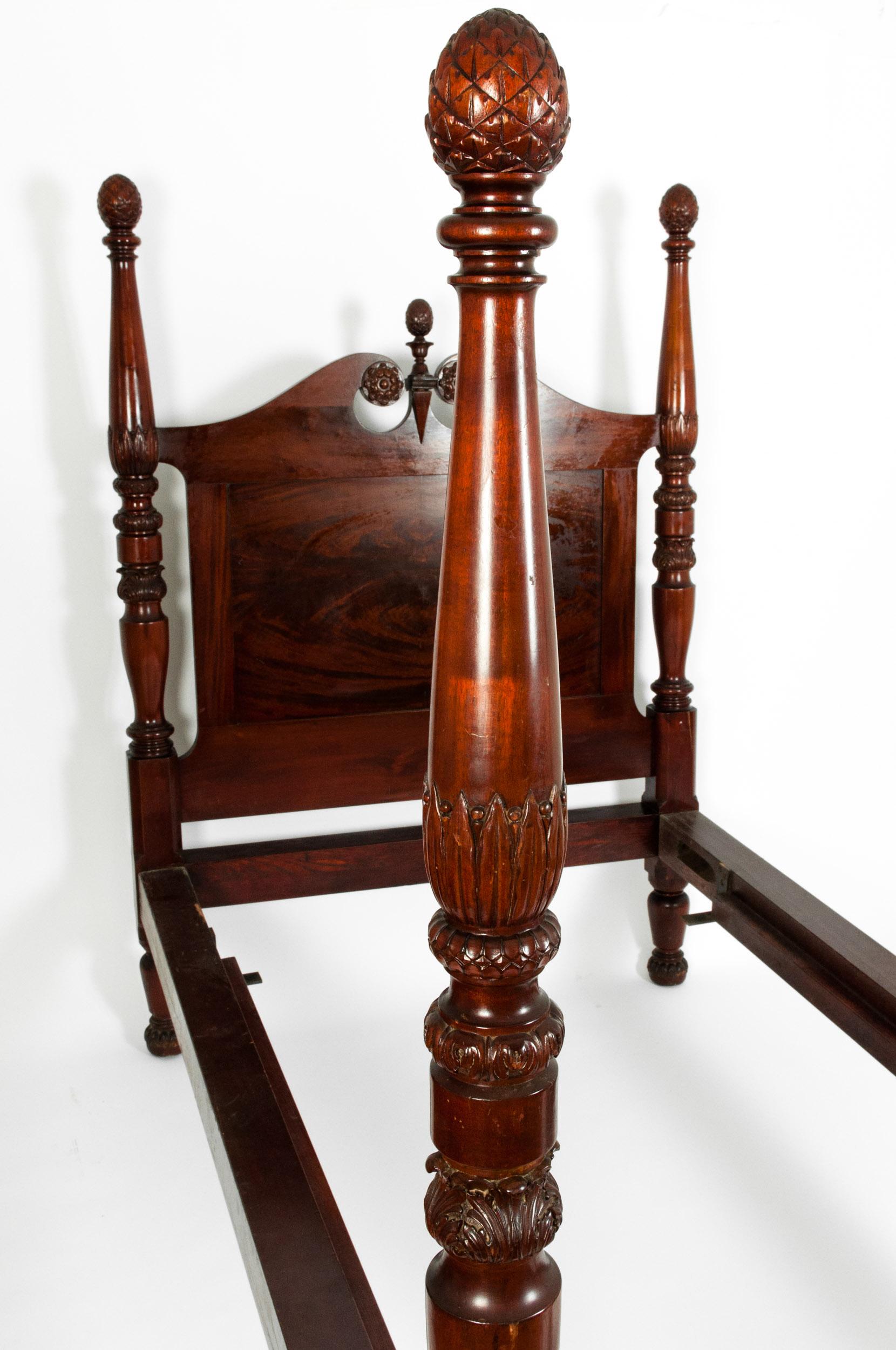 Mid-19th century empire style mahogany wood four poster single bed with hand carved design details. The bed is in good antique condition with appropriate wear consistent with age / use. The Pineapple head piece have been repaired .  The bed measure