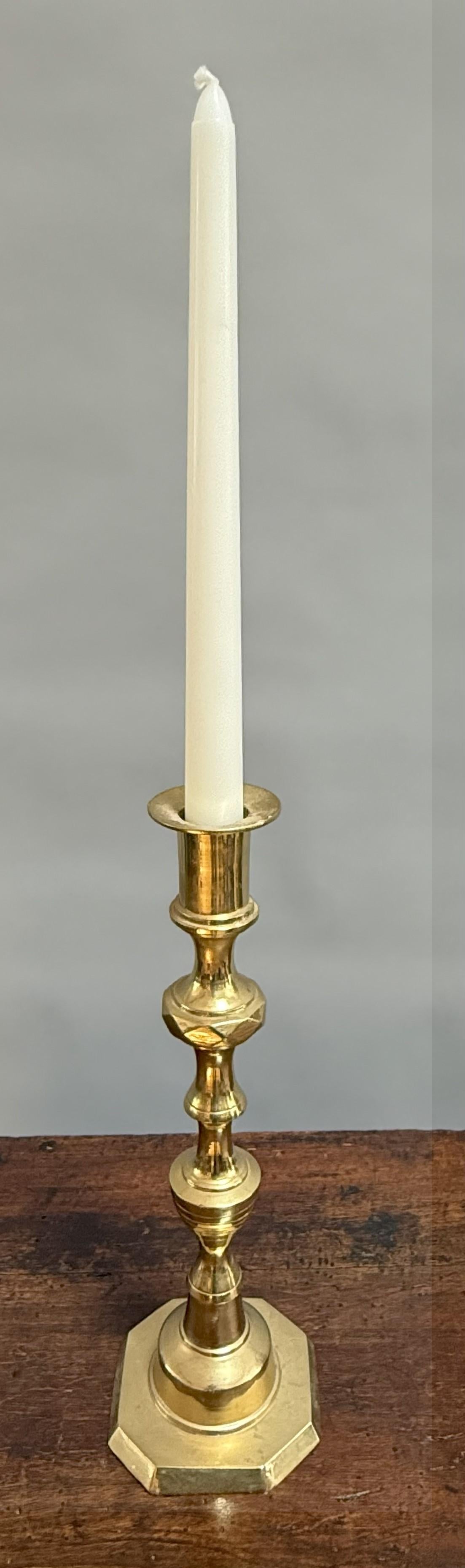 A charming single brass candlestick from England, dating to the Victorian era, circa 1870. Beautifully executed in brass, the candlestick rises with a sculptural baluster stem enriched by faceted and ring-turned detailing, set above a stepped