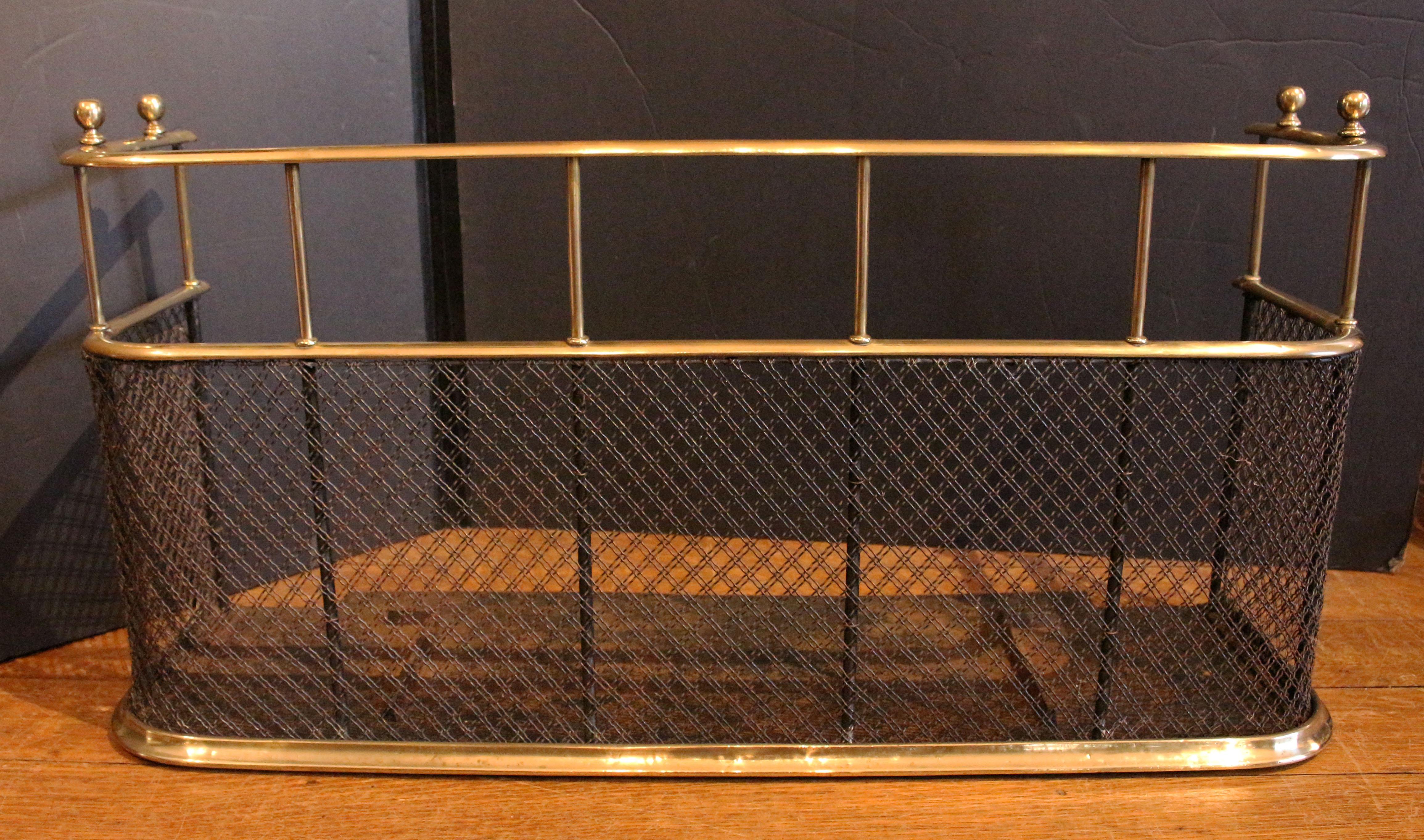 Mid-19th century English brass fire fender with double cross iron mesh. Integral tool rest stops at each end to hold tools in place. Often this taller form which completely surrounds the fire is called a nursery guard or nursery fender. Iron hearth