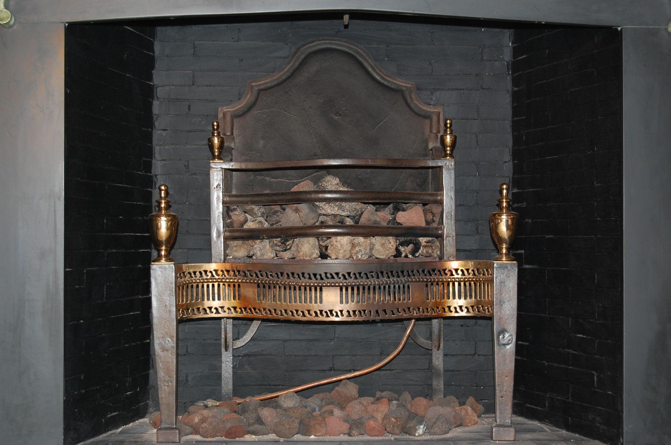 A mid-19th century brass and steel fire grate, with square tapering front supports surmounted by classical finials. A pierced brass fret work design and beading. The cast iron fire back is arched and does have a vertical crack, see notes below.