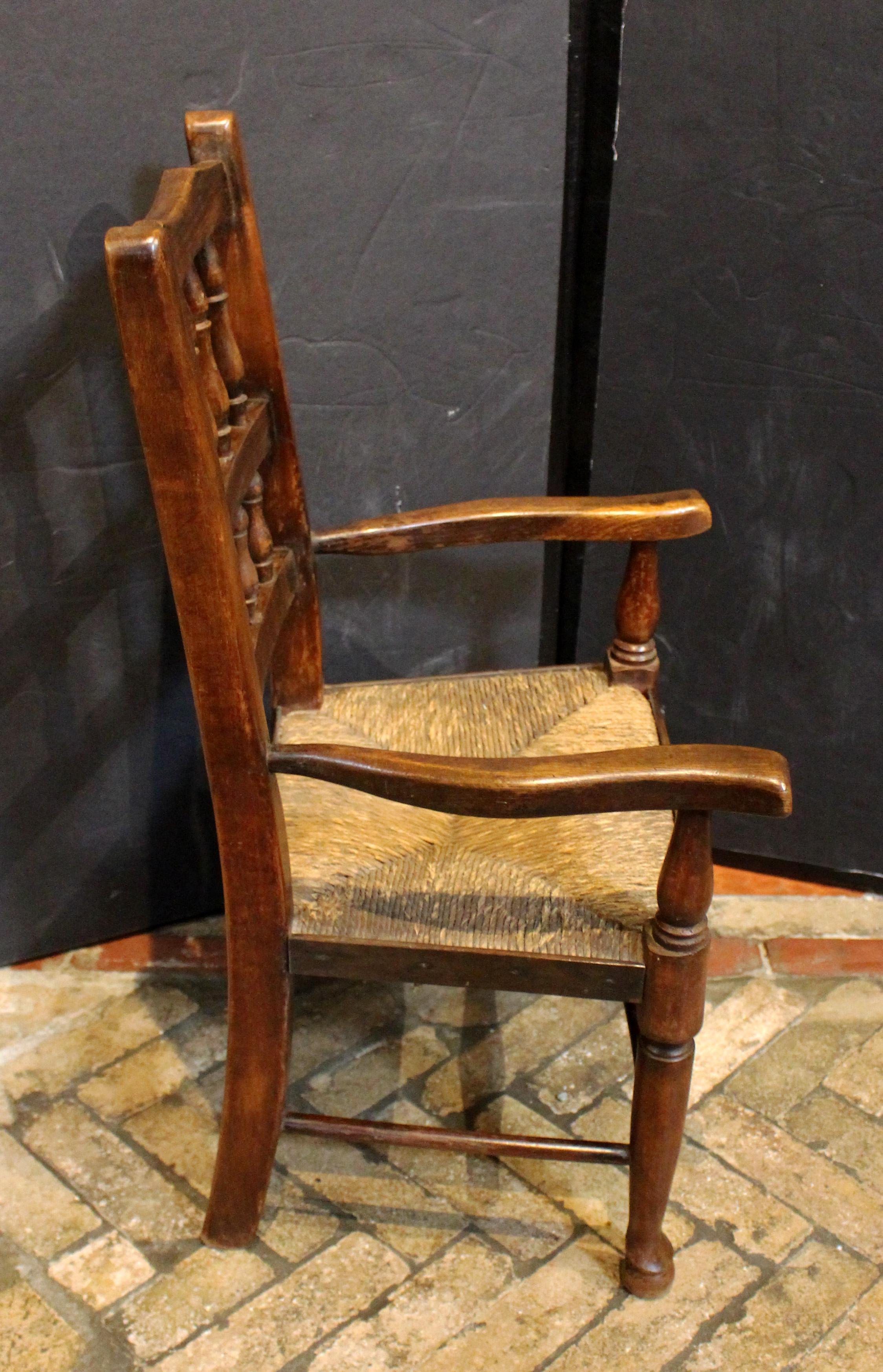 Mid-19th century English Lancashire Child's Arm Chair. Typical Lancashire Queen Anne style. Rarely found child's size. Charming with good vasi-form turnings along the back; shaped arms; pad feet; & turned stretchers. Good old rush in fit