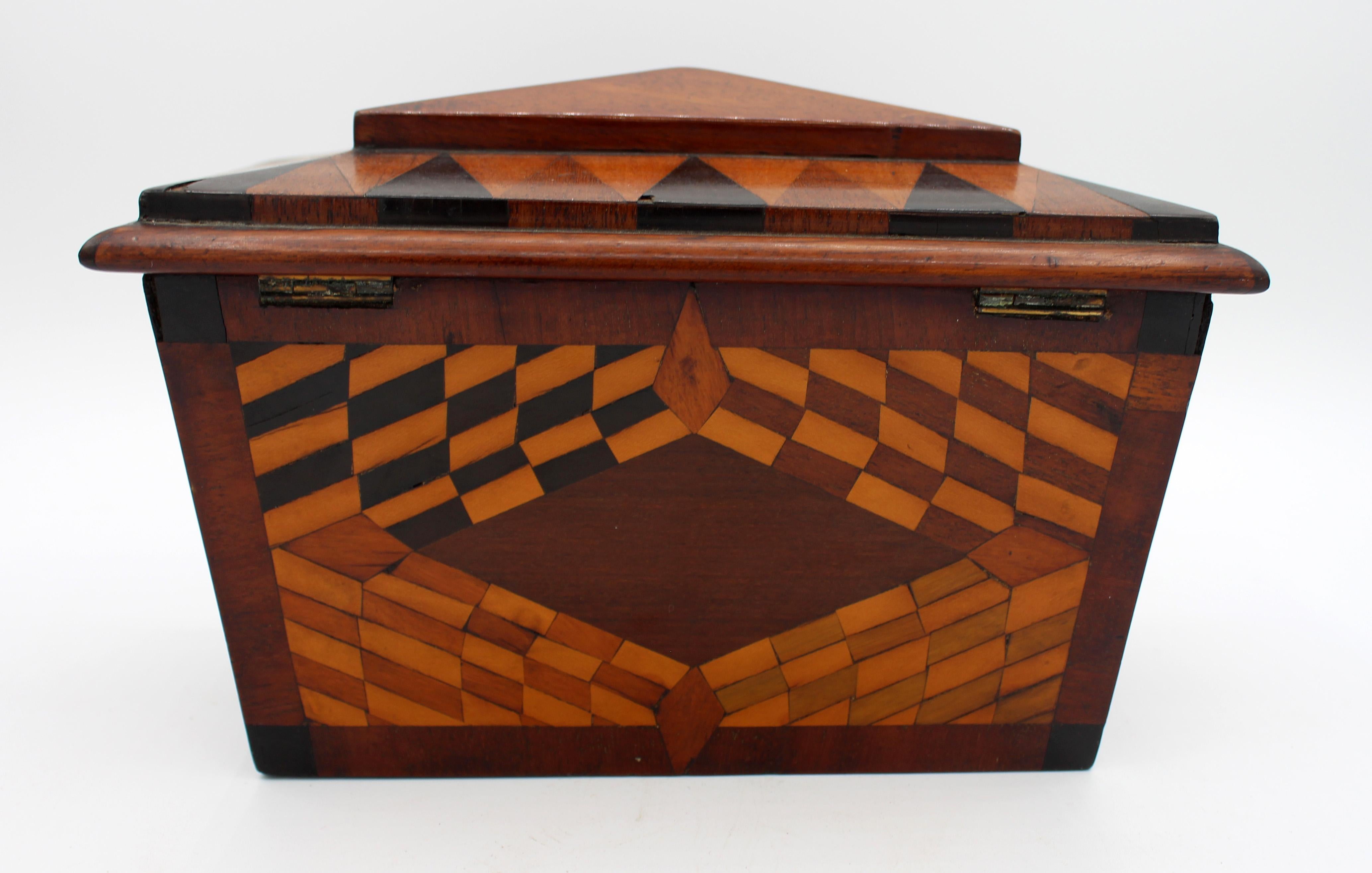 Mid-19th century parquetry inlaid tea caddy box. English. Extensive parquetry work mahogany, ebony, satinwood & dyed sycamore to each side and in the interior of the lid. Tea covers intact with ebony turned pulls. Minor veneer losses.
Measures: 8