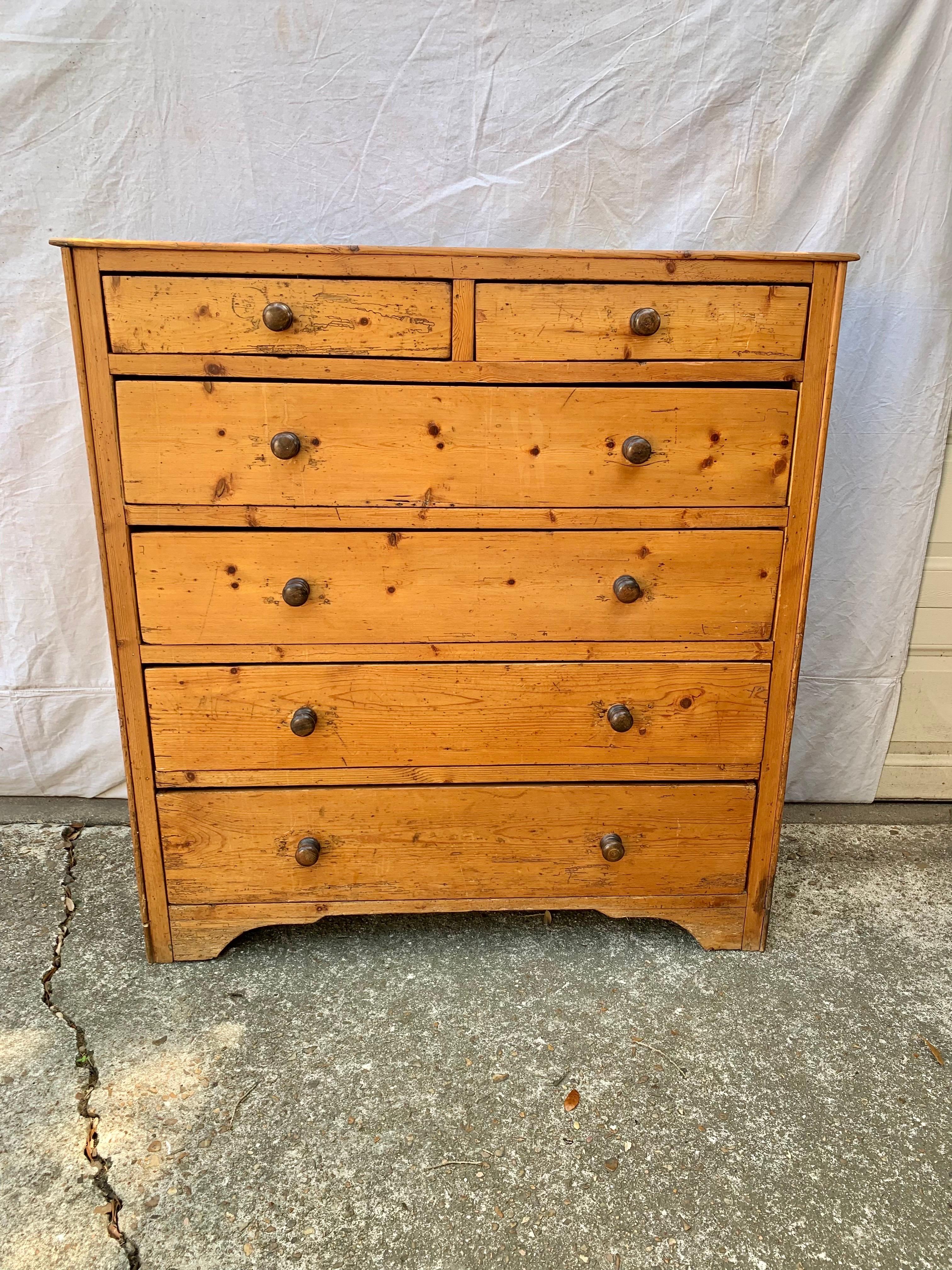 Found in England, this Chest of Drawers or Commode was crafted in the Mid 19th Century by English artisans from old growth Pine. Constructed with a two plank top resting above six drawers, 2 smaller at the top and four lower, the piece provides