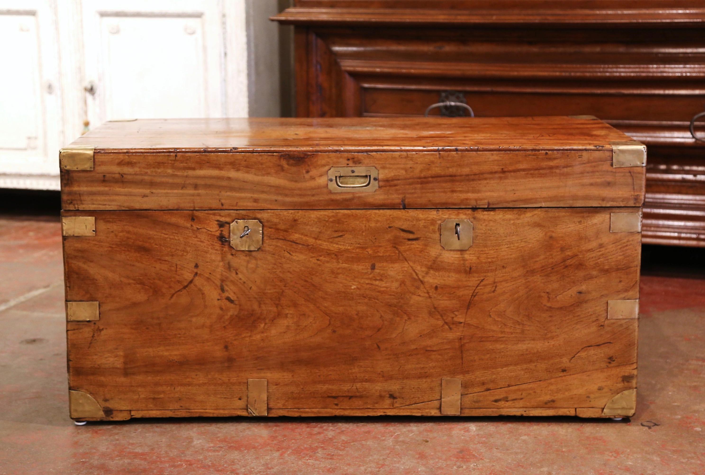 Decorate a den or living room with this elegant antique coffer cocktail table. Crafted in England circa 1870 and finished on all five sides, the trunk is built of solid walnut and decorated with brass angle brackets on the sides and corners. The