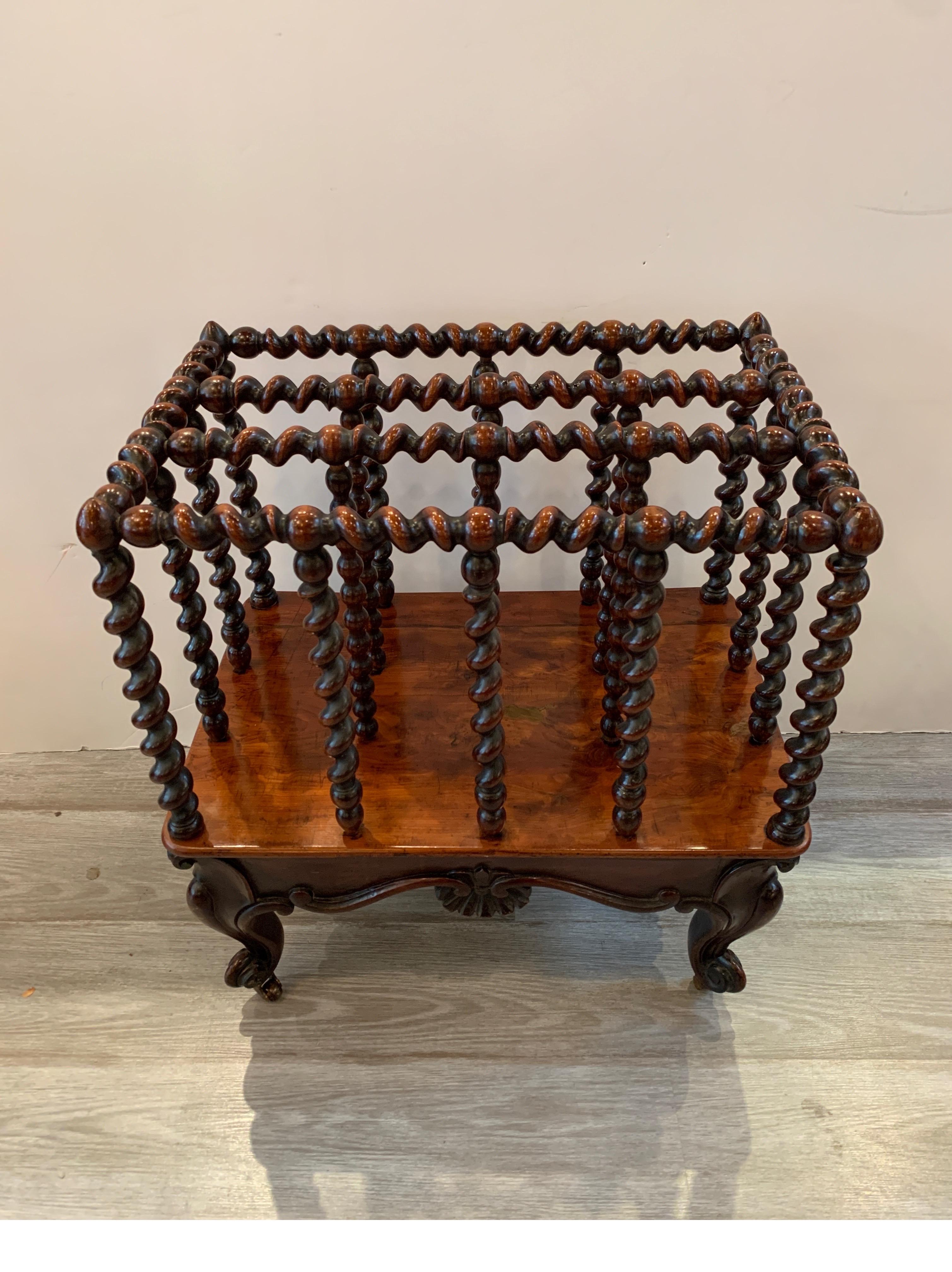 The barley twist compartments at the top with a hand carved base with four cabriole legs resting on original brass castors. Great for newspapers, magazines and sheet music. Measuring: 21