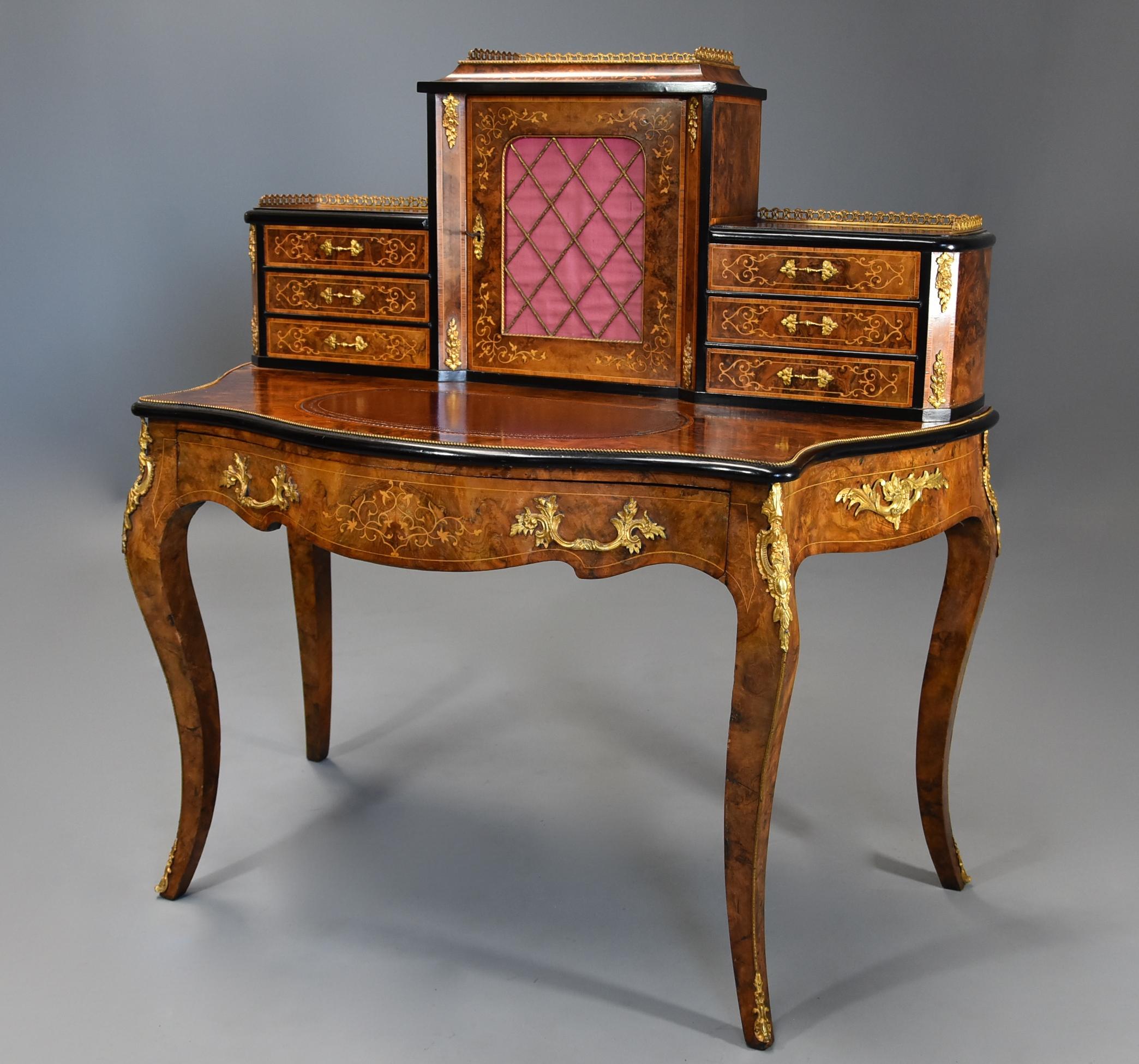 A mid-19th century fine quality burr walnut bonheur de jour in the French style. 

This piece consists of a structure of six small drawers to the top, three drawers to either side of the cupboard with fine quality pierced brass gilt gallery to the