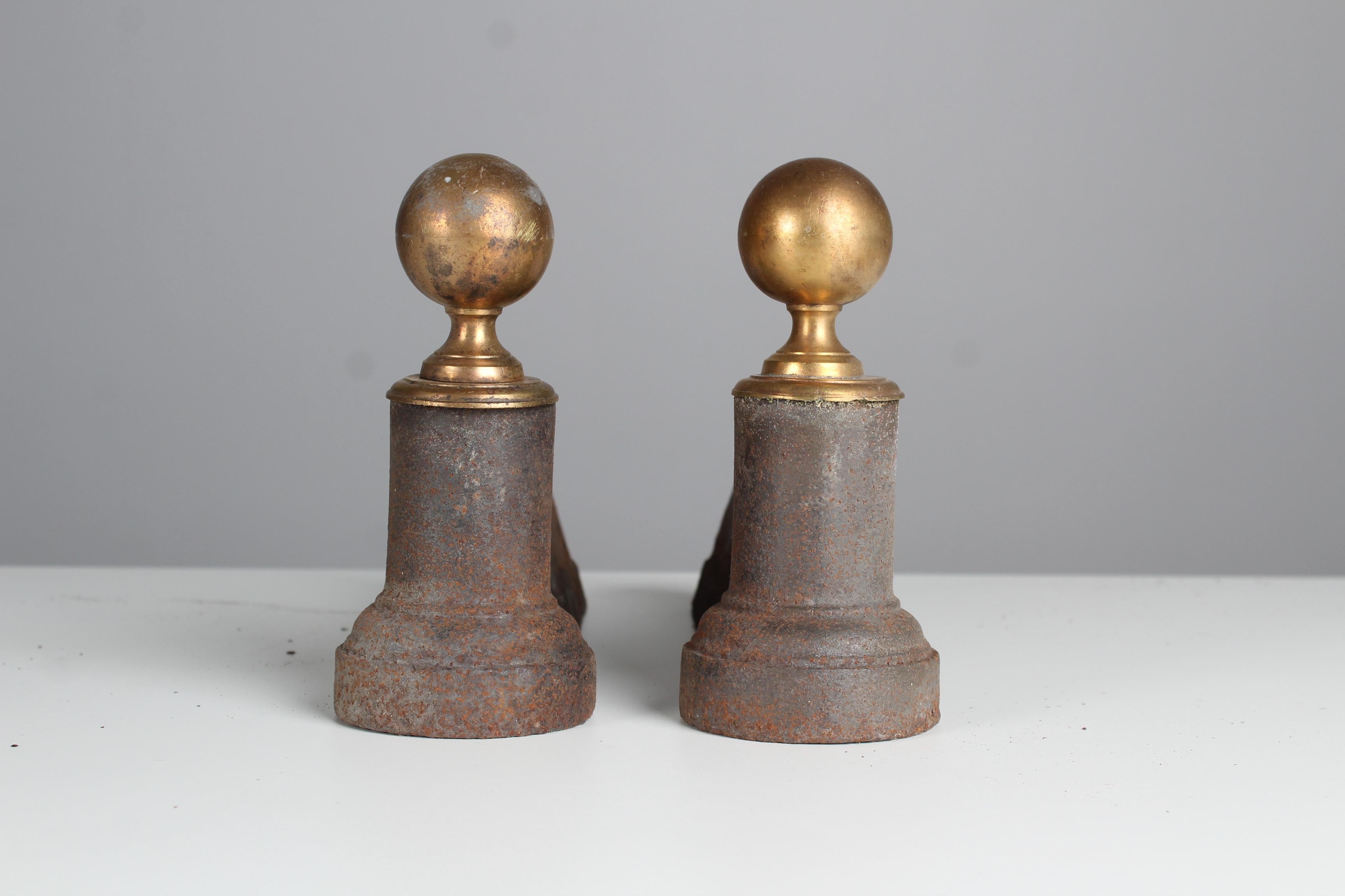 Pair of wonderful andirons with a brass globe decoration.
France, circa 1860.
Solid iron in good condition according to its age.

Firedogs are used as a holder for firewood in a fireplace. They are also known as a fire horse, andiron or chimney