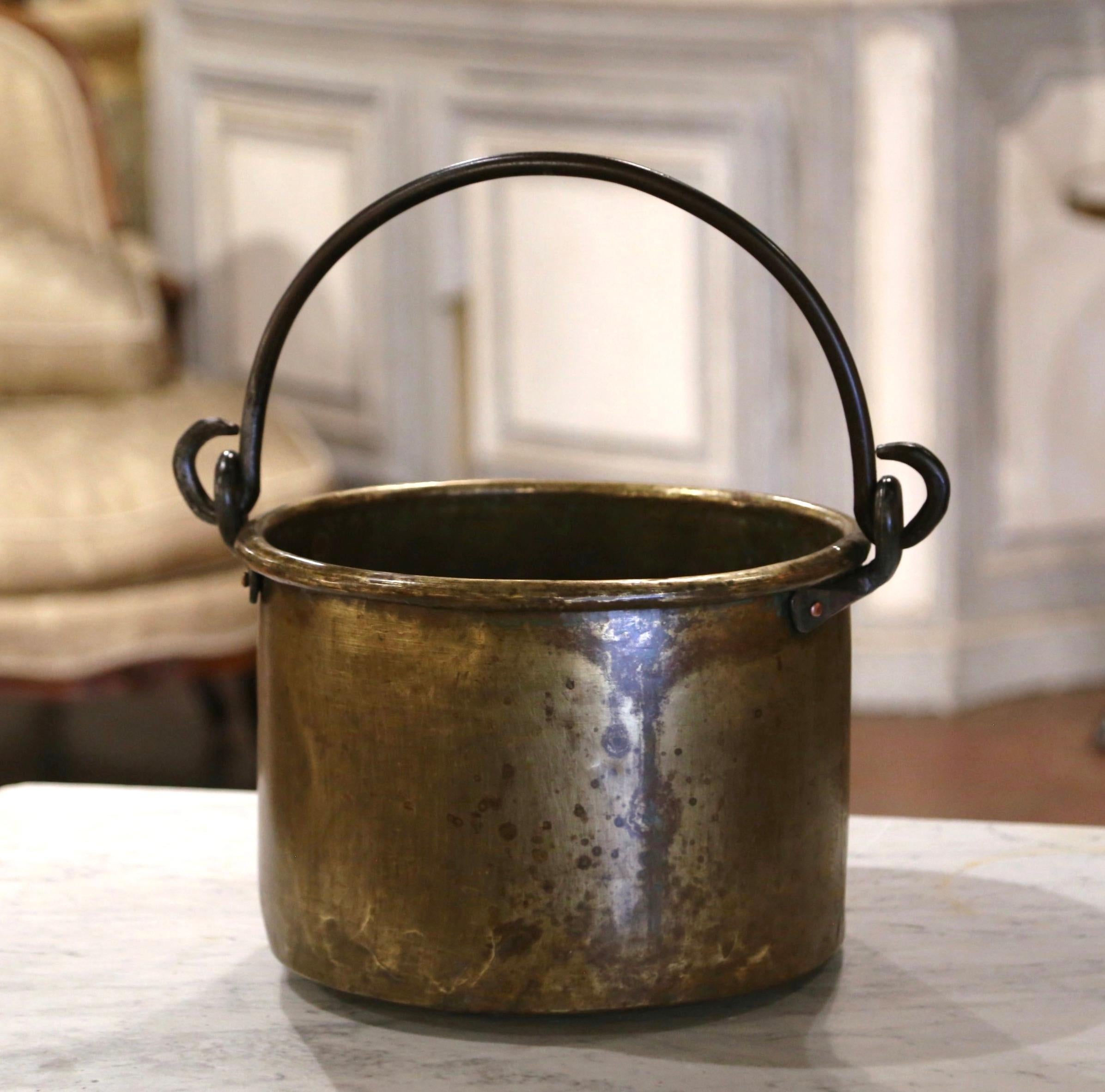 Apportez une touche authentique de campagne française à votre cuisine avec ce grand pot d'allumage antique. Fabriqué en Normandie, France, vers 1870, l'important cache pot est de forme ronde et habillé d'une anse en fer forgé fixée par des rivets.