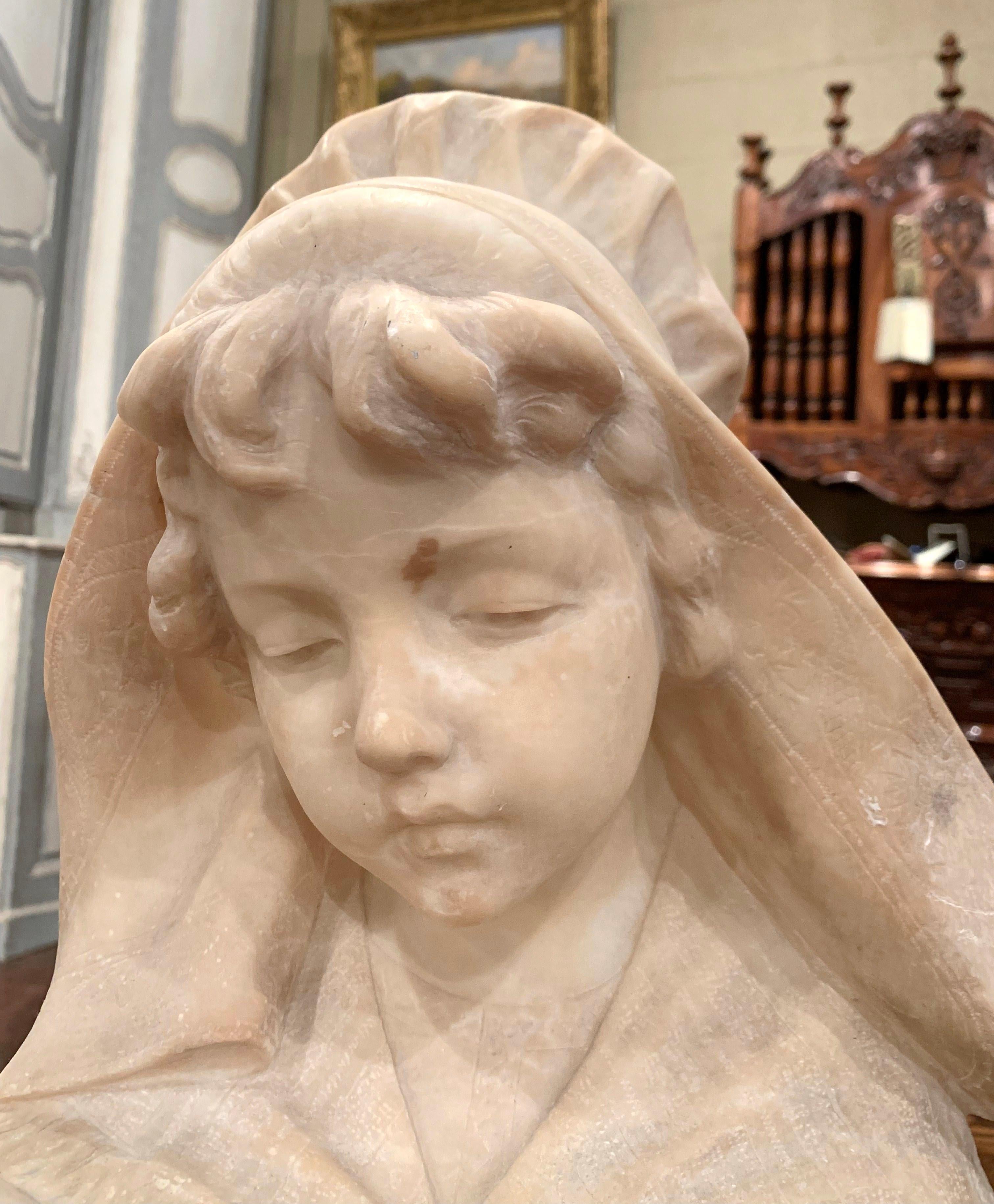 Crafted in France circa 1850, this large antique marble bust is a true representation of French elegance. The figural sculpture features the visage of a beautiful young beauty; she is dressed in a lace shawl over her shoulders, and holding a