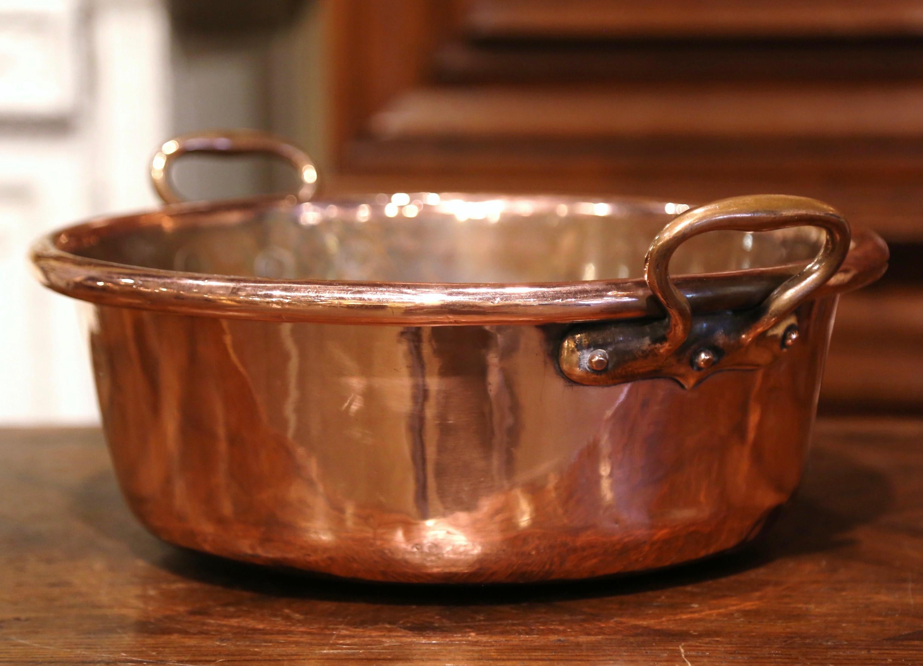 Bring an authentic French countryside touch to your kitchen with this large antique copper marmalade bowl. Crafted in Normandy, France, circa 1870, the decorative “Bassine a Confiture” (jam bowl) is round in shape and dressed with two brass side