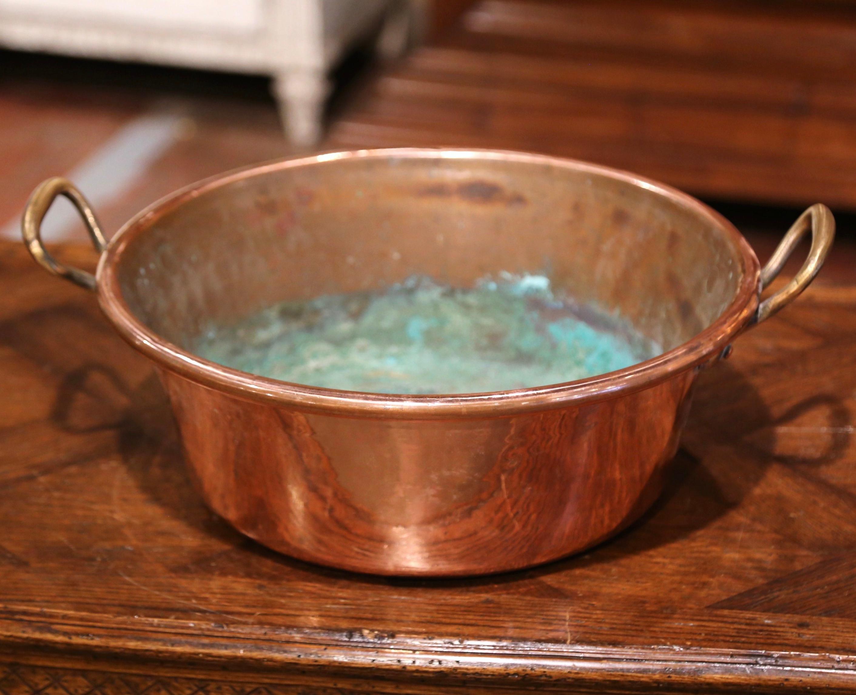 Bring an authentic French countryside touch to your kitchen with this large antique copper marmalade bowl. Crafted in Normandy, France, circa 1870, the decorative “Bassine a Confiture” (or jam bowl) is round in shape and dressed with two brass side