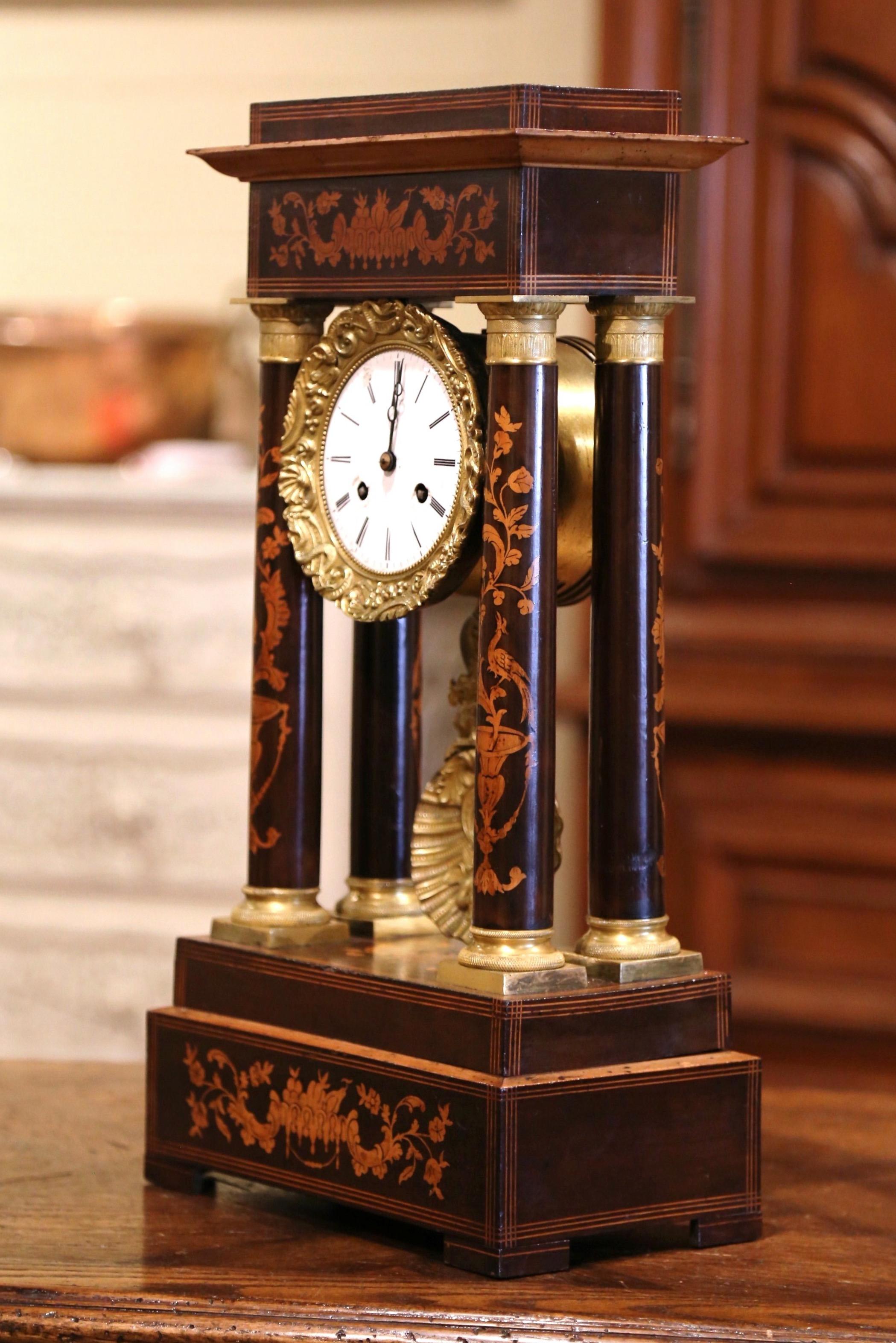 Keep time in your office, study, or atop your mantel with this elegant antique clock. Crafted in France, circa 1860, the sophisticated clock stands on a rectangular plinth base with contrasting foliate marquetry. The clock features four columnar
