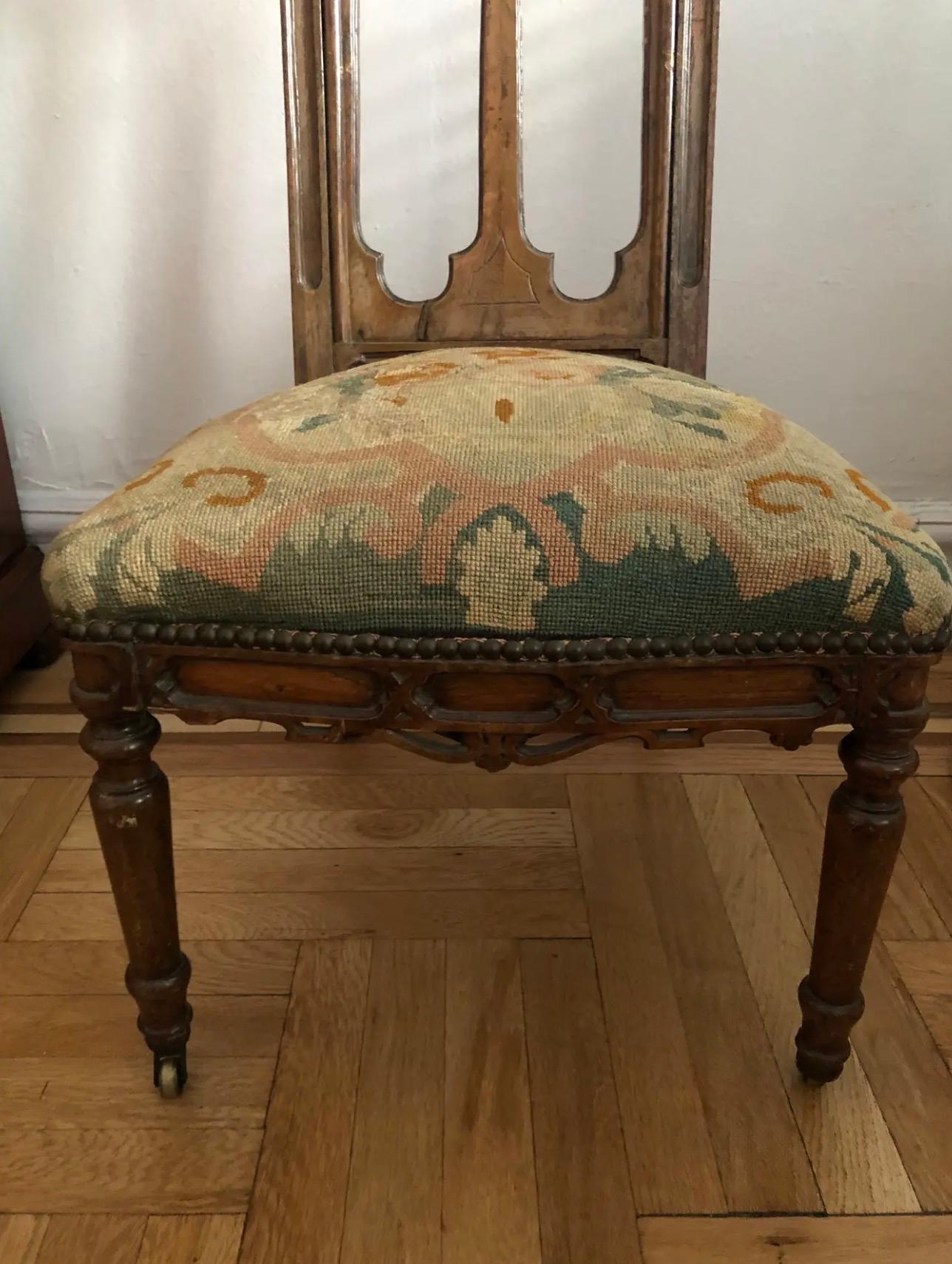 Una poltrona gotica ricca di dettagli proveniente dalla Francia della metà del XIX secolo, con una struttura in legno di quercia intagliata a mano e una tappezzeria originale a punto d'ago. Questo maestoso pezzo incarna la grandezza e l'eleganza