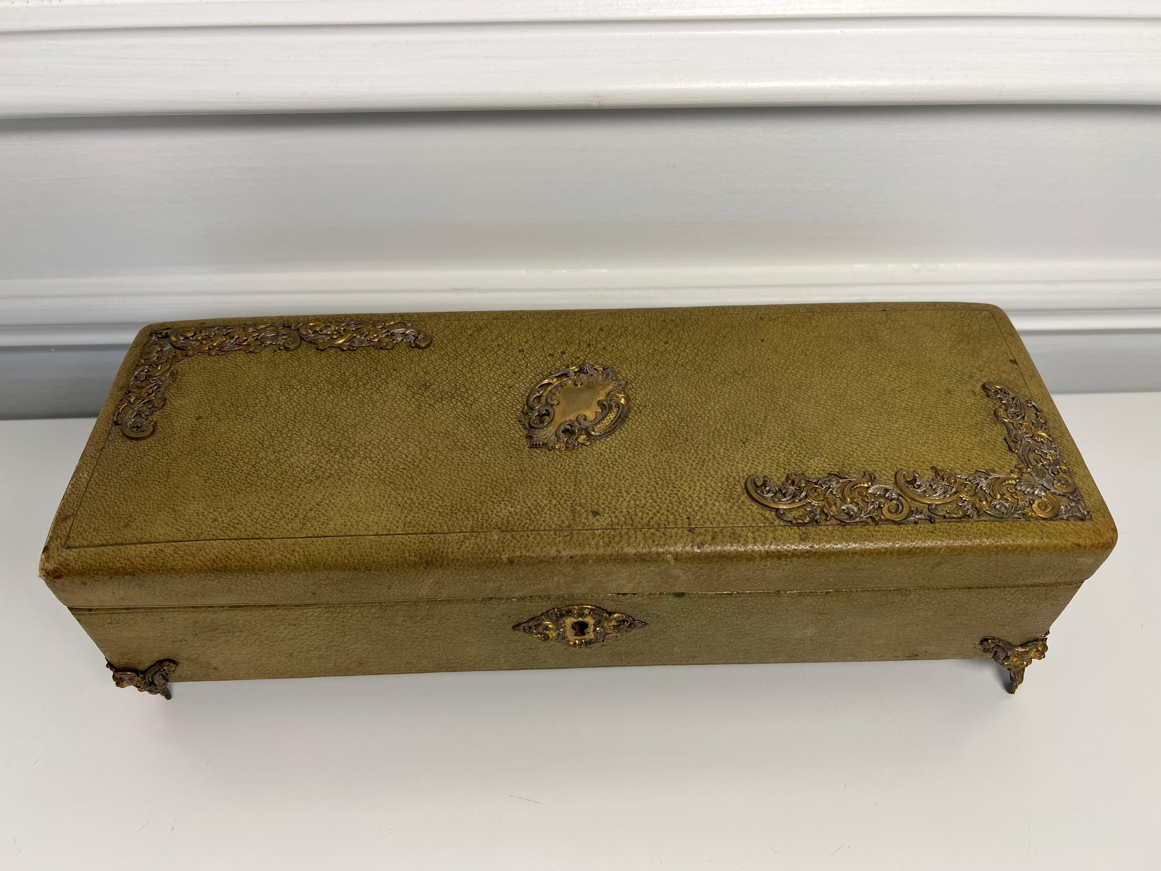 A nice early French green leather glove box with brass ormolu on four decorative brass feet, with a beautiful pink silk interior. This is from a private collector who traveled the world buying great pieces.